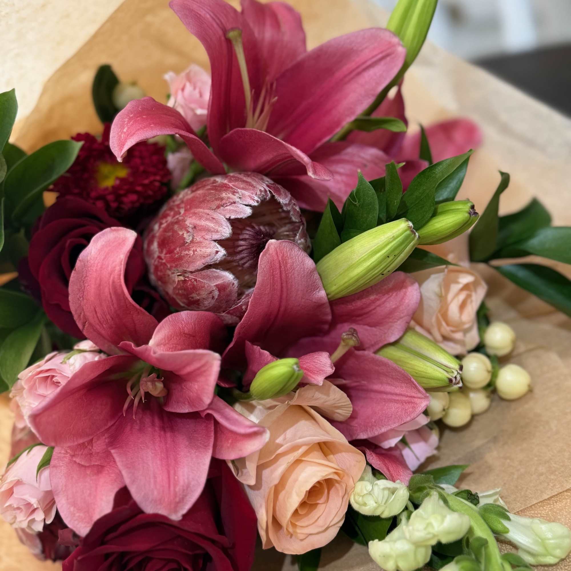 Bouquet of pink lilies and roses wrapped in tan paper