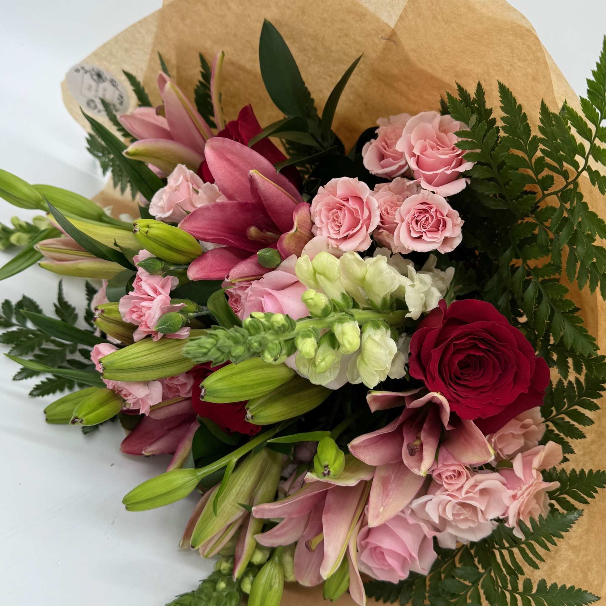Pink lilies and roses wrapped in brown paper