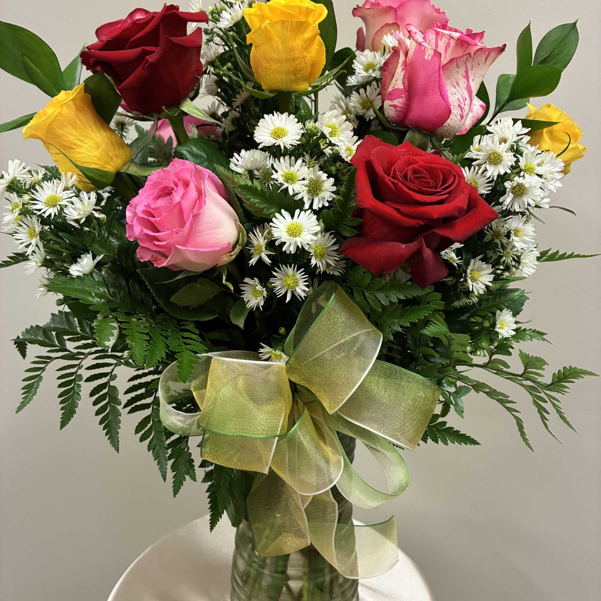 Bouquet of multicolored roses and white daisies in a glass vase