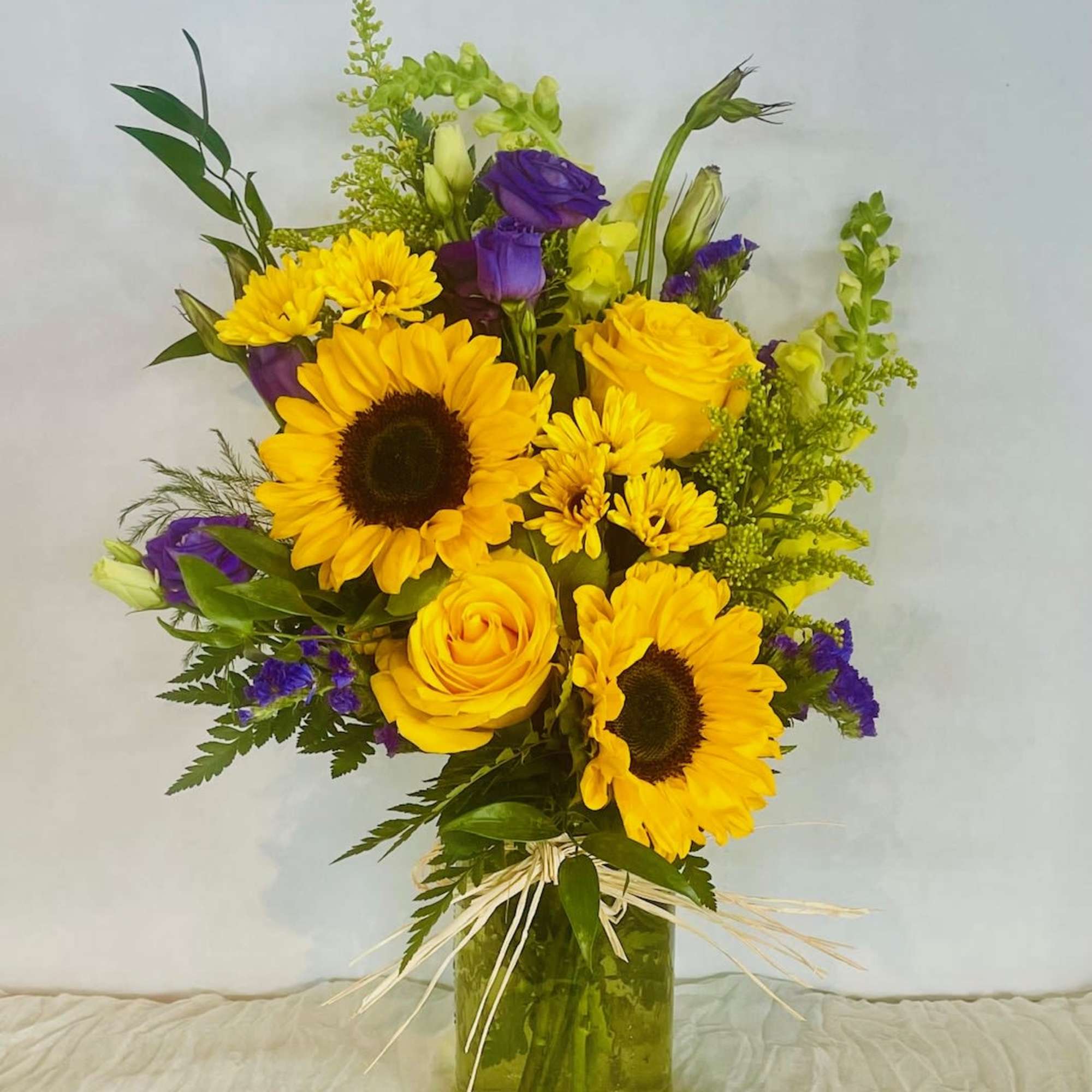Bouquet of yellow sunflowers and roses in a glass vase