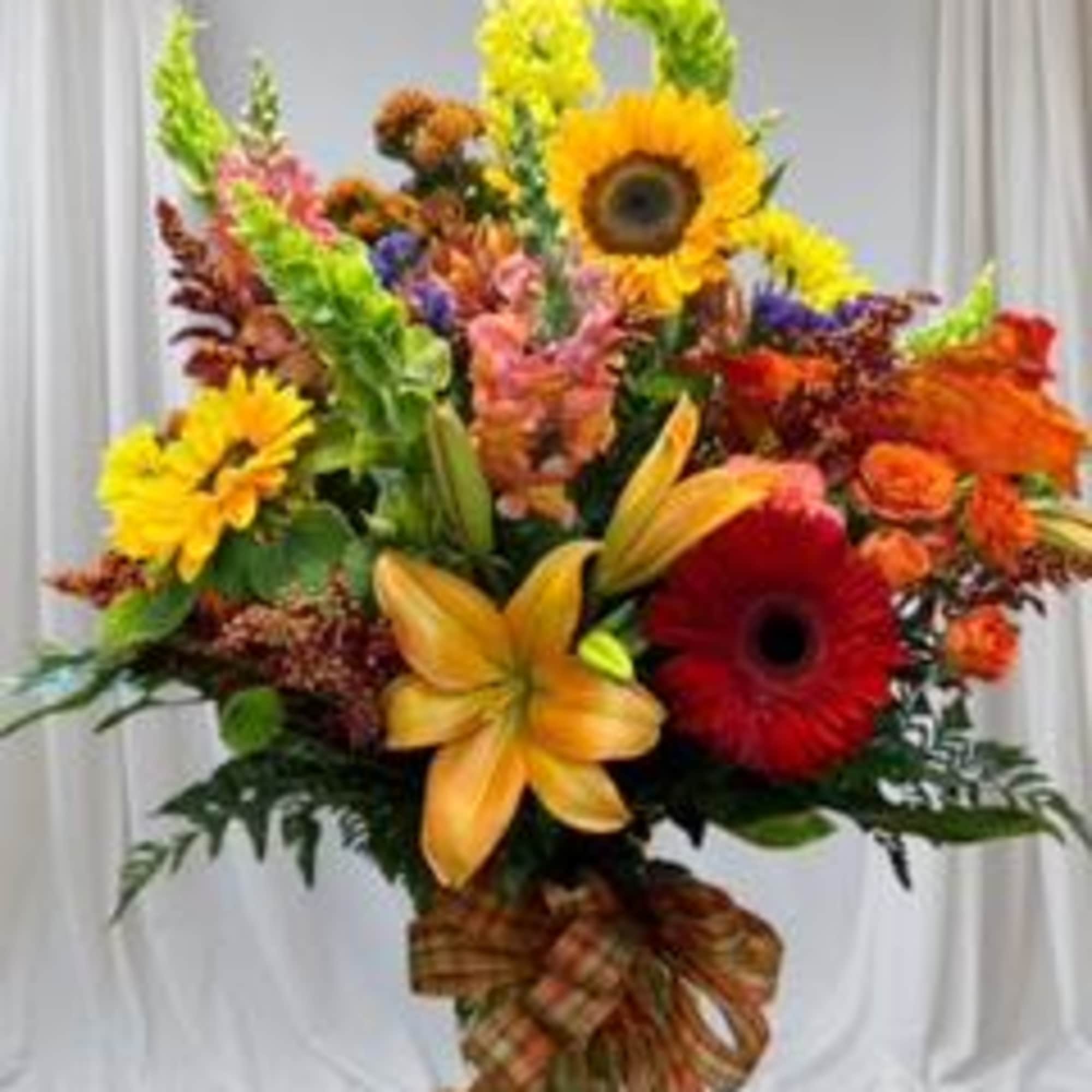 Colorful mixed bouquet with sunflowers, lilies, and gerbera daisies in a glass vase