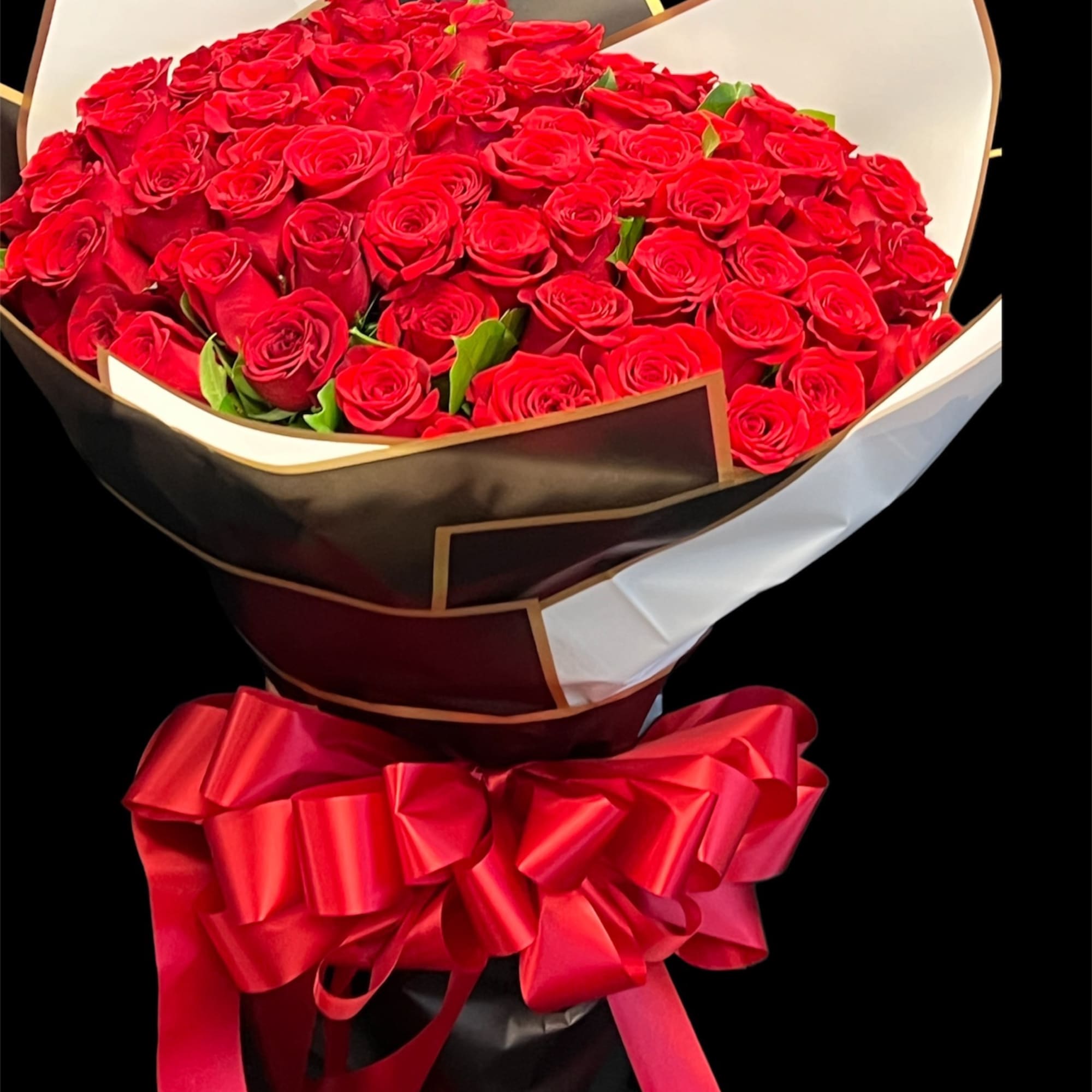 Large bouquet of red roses wrapped in black and white paper with a red ribbon