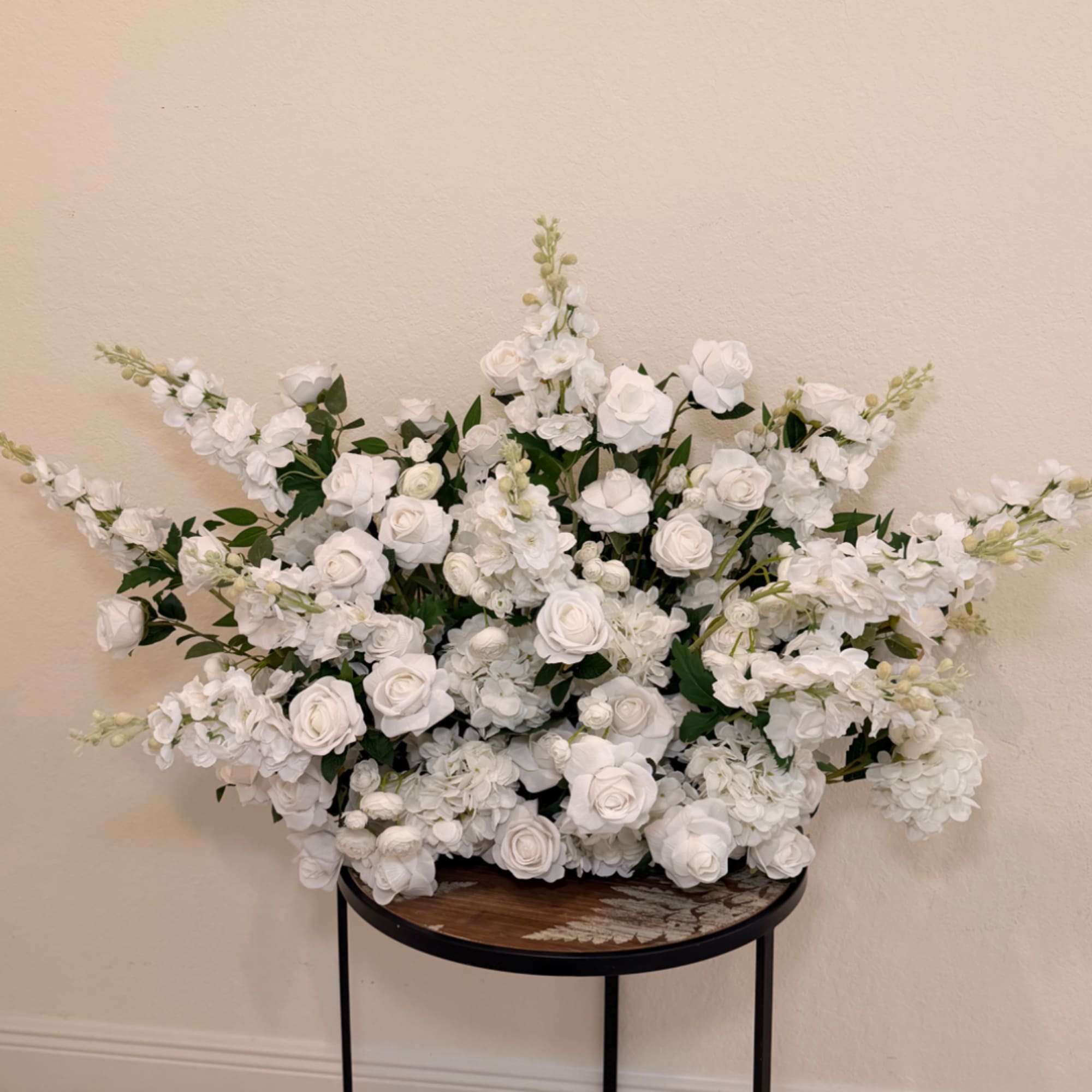 Large white floral arrangement with roses and blossoms on a round table