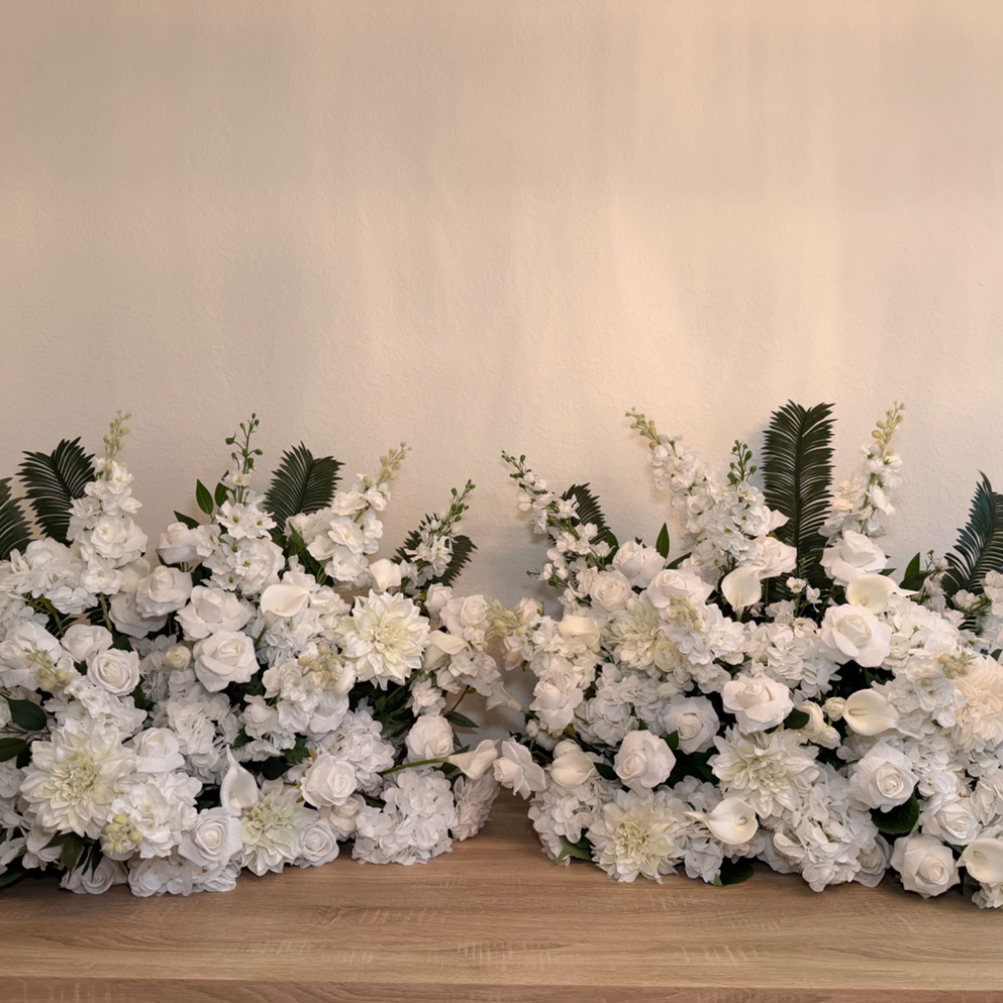 White floral arrangements with roses, hydrangeas, and calla lilies on a table