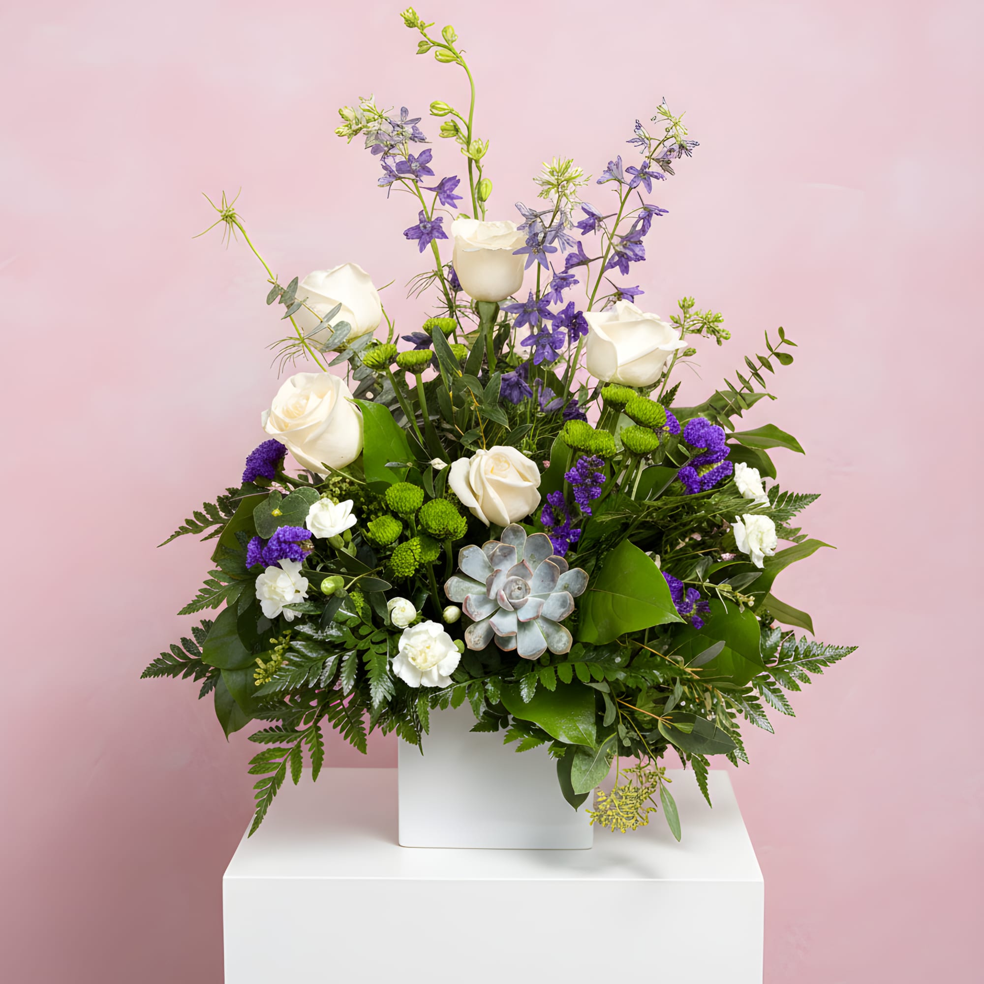 White roses and purple flowers arranged in a white vase