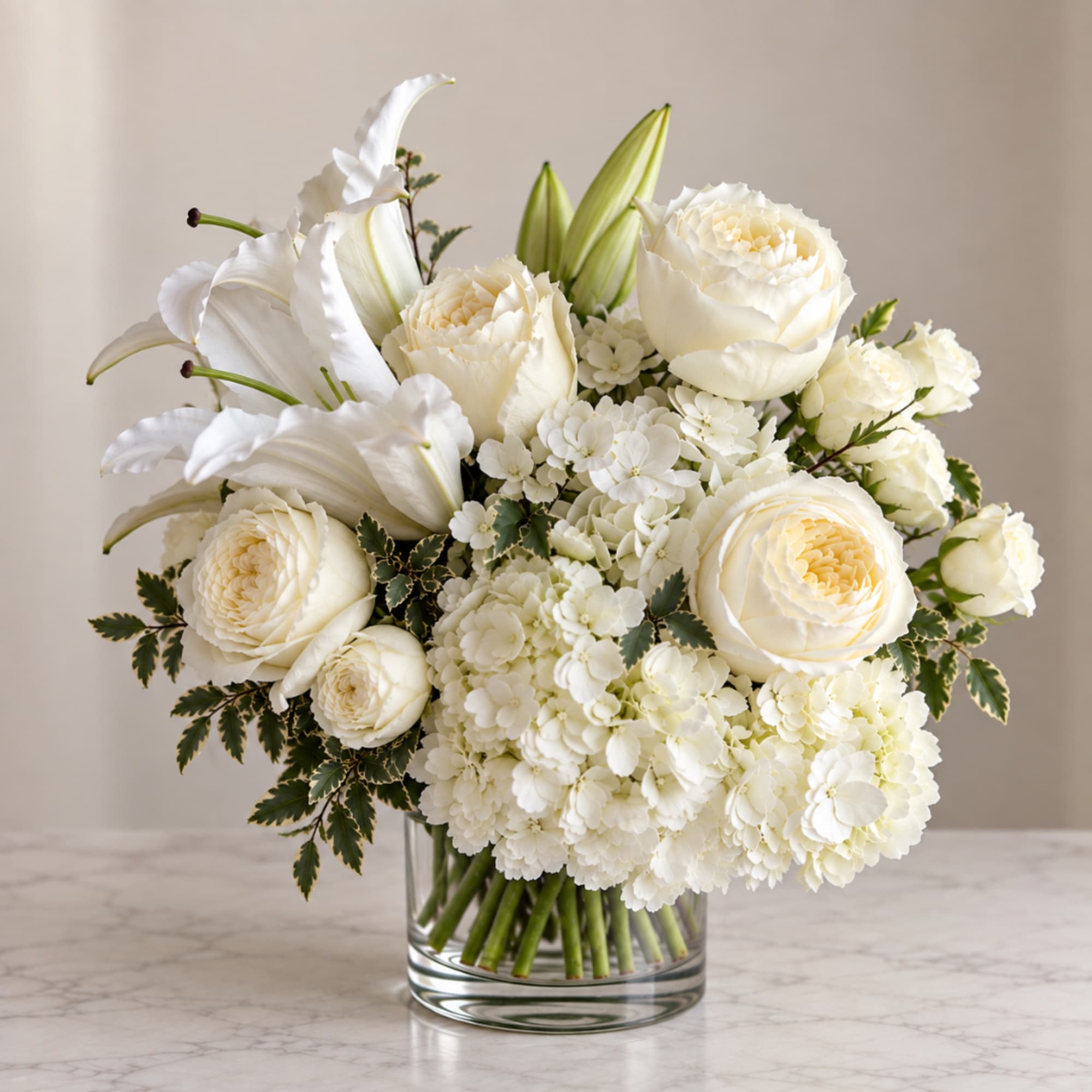 White roses and lilies arranged in a clear glass vase