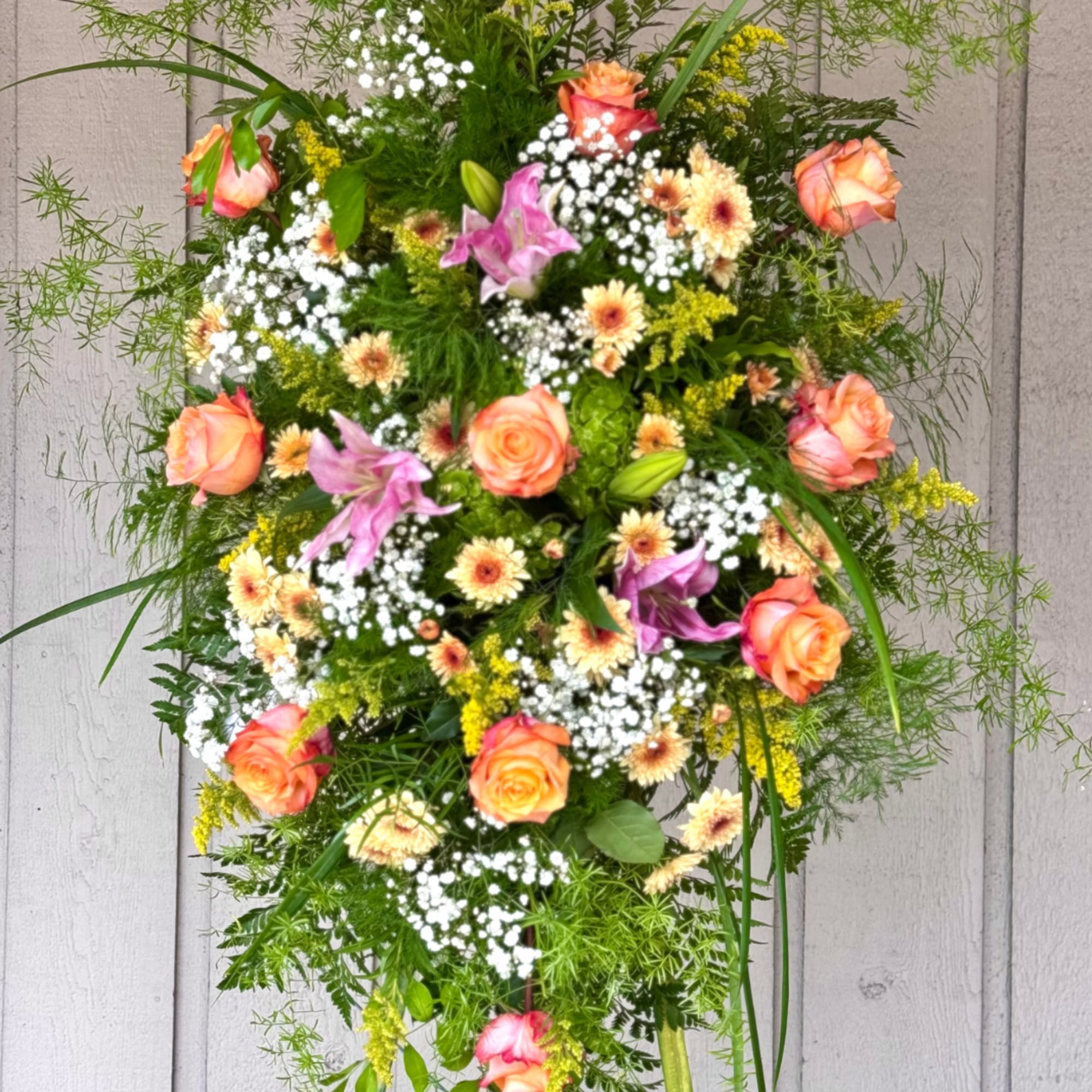 Tall floral spray with peach roses, lilies, and white filler flowers