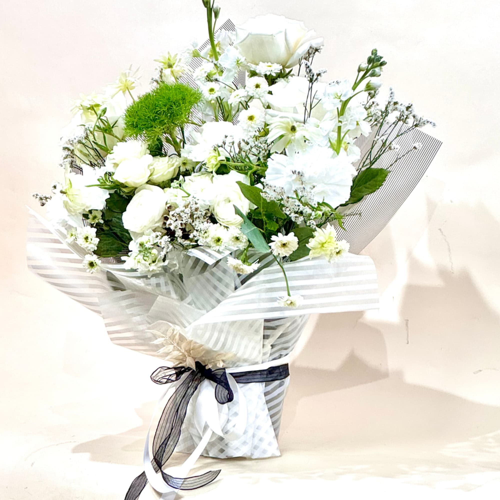 White bouquet with small blooms and a black ribbon wrap