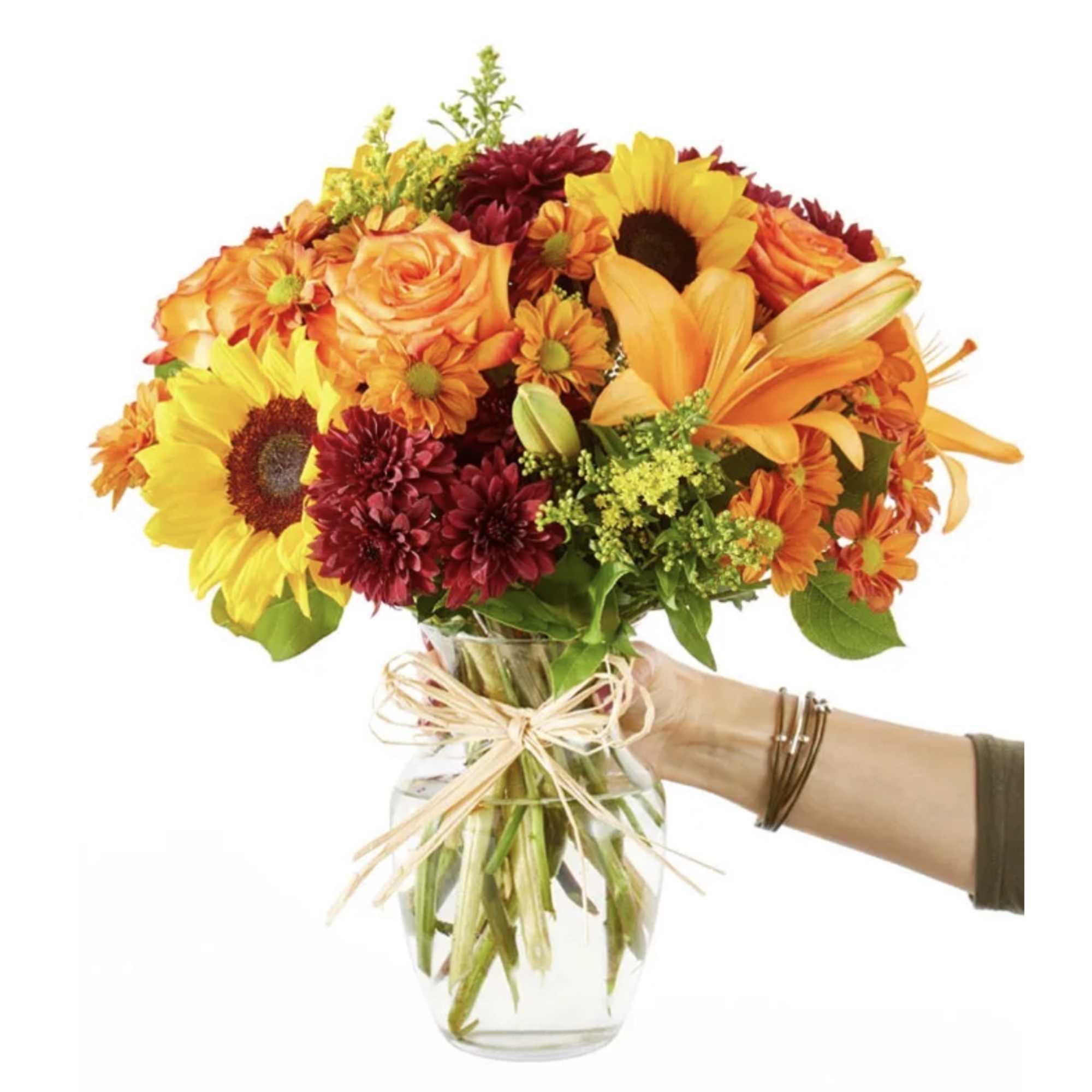 Bouquet of sunflowers, roses, and mums in a glass vase with ribbon