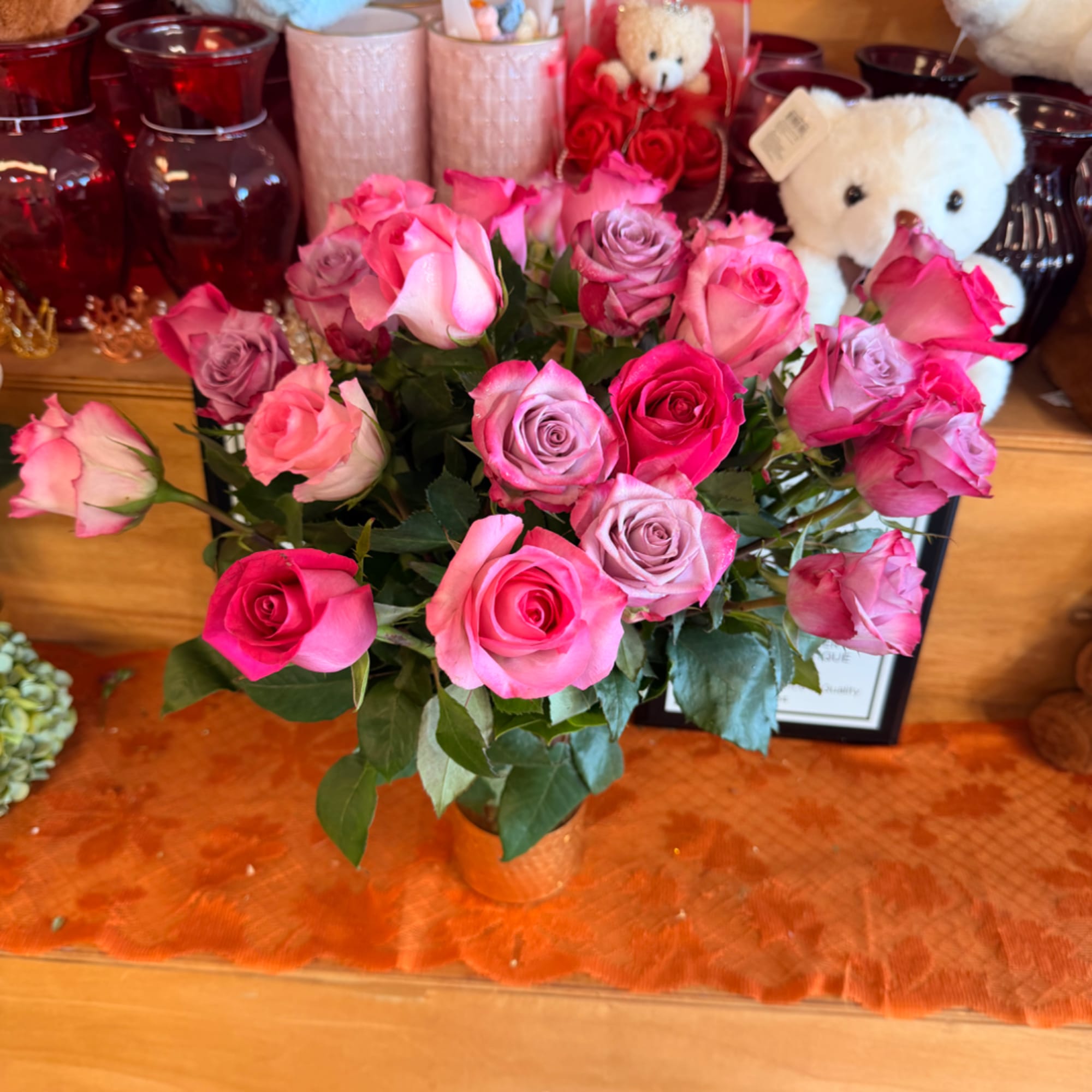 Bouquet of pink and lavender roses in a vase with teddy bears behind it