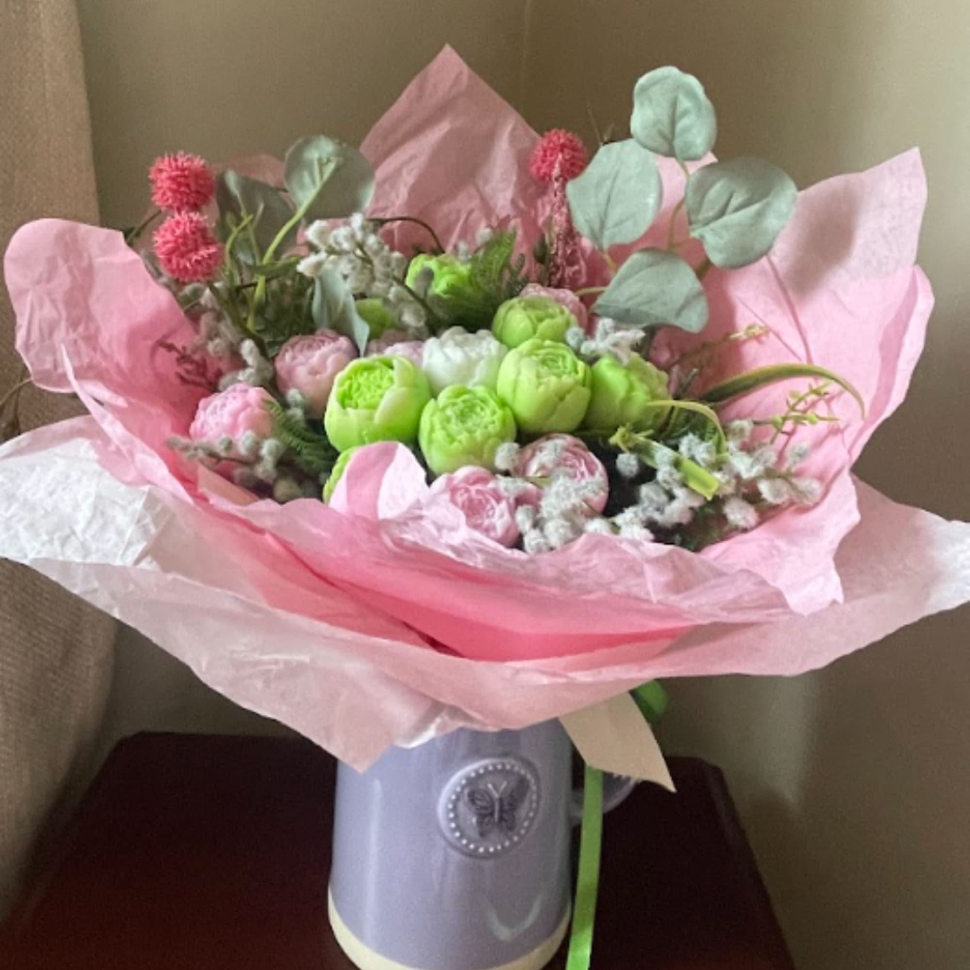 Pink and green bouquet in a lavender vase with tissue wrap
