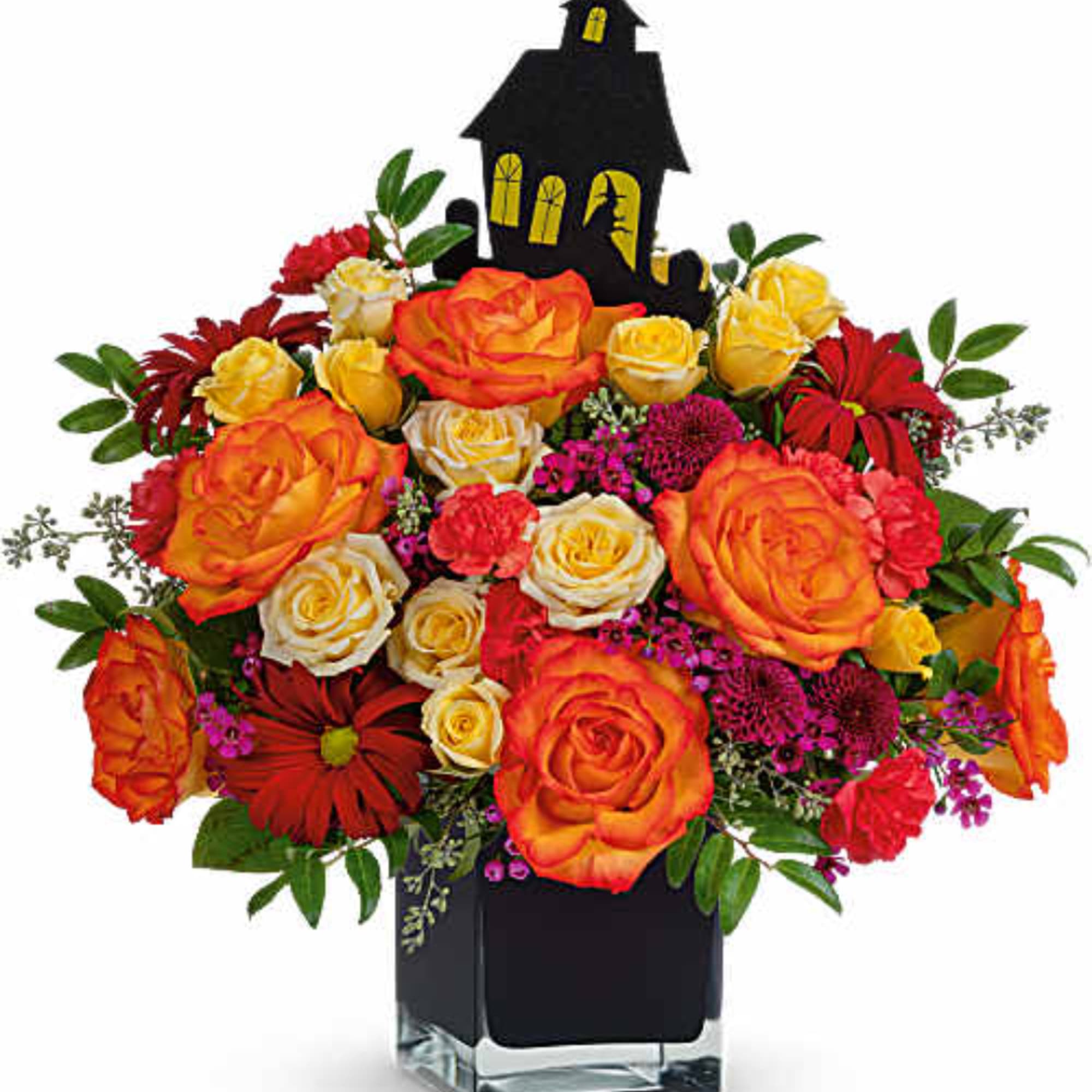 Orange and yellow roses arranged in a black vase with a Halloween house topper