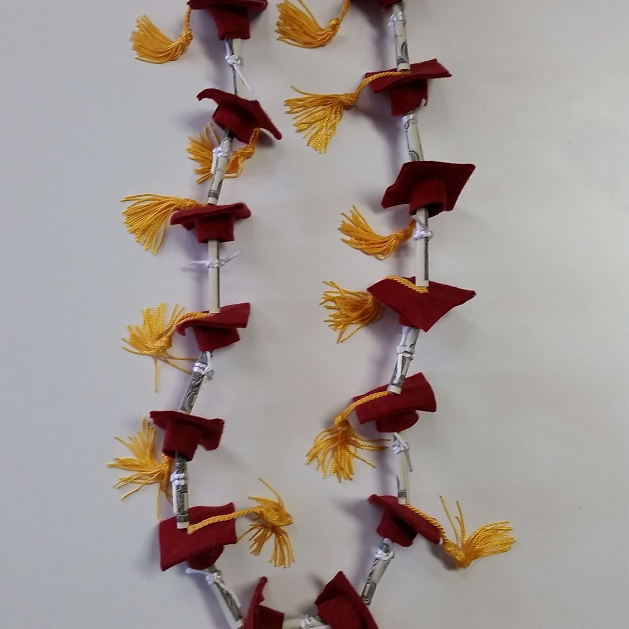 Maroon graduation stole with gold tassels hanging on a wall
