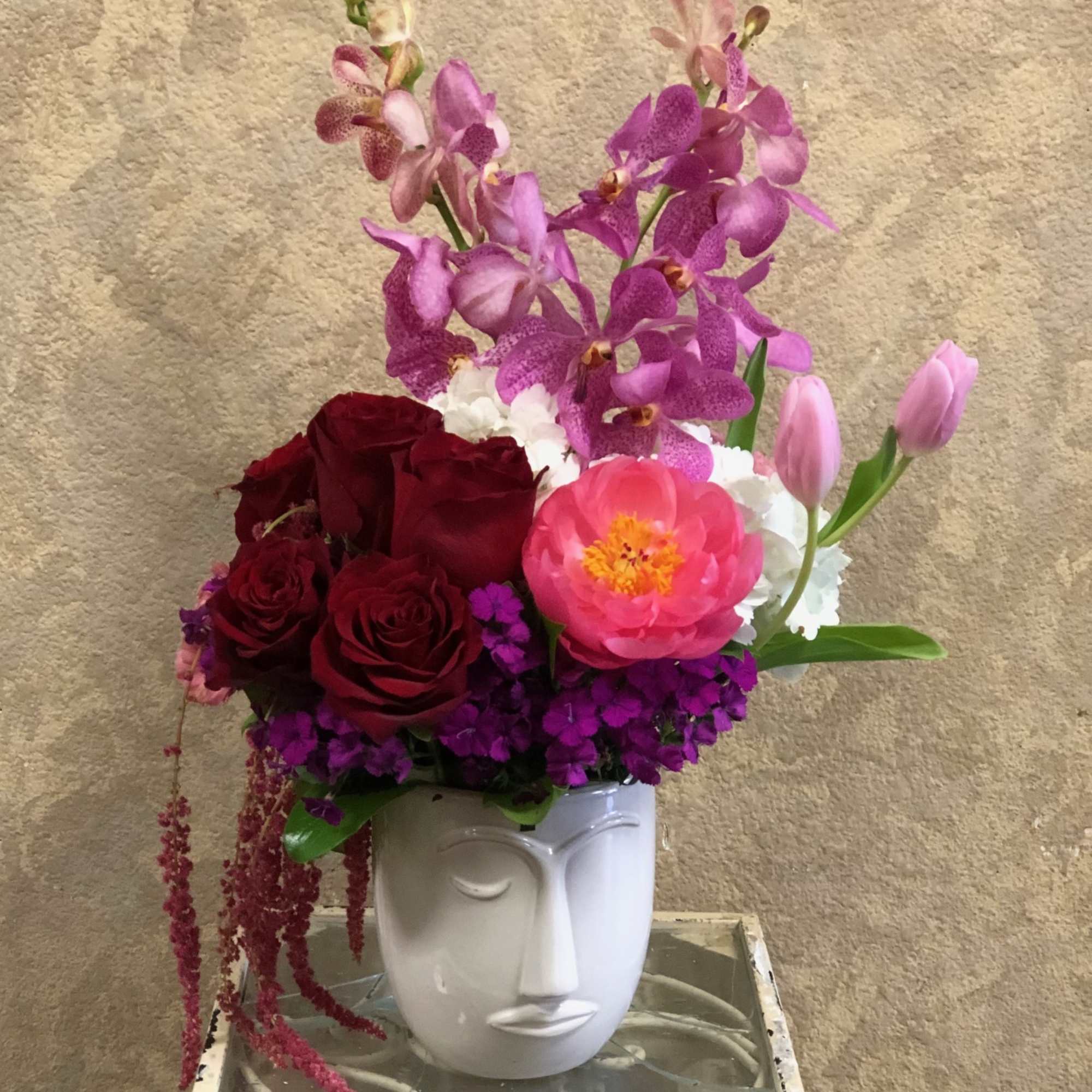 Mixed bouquet in a white face-shaped vase with pink and red flowers