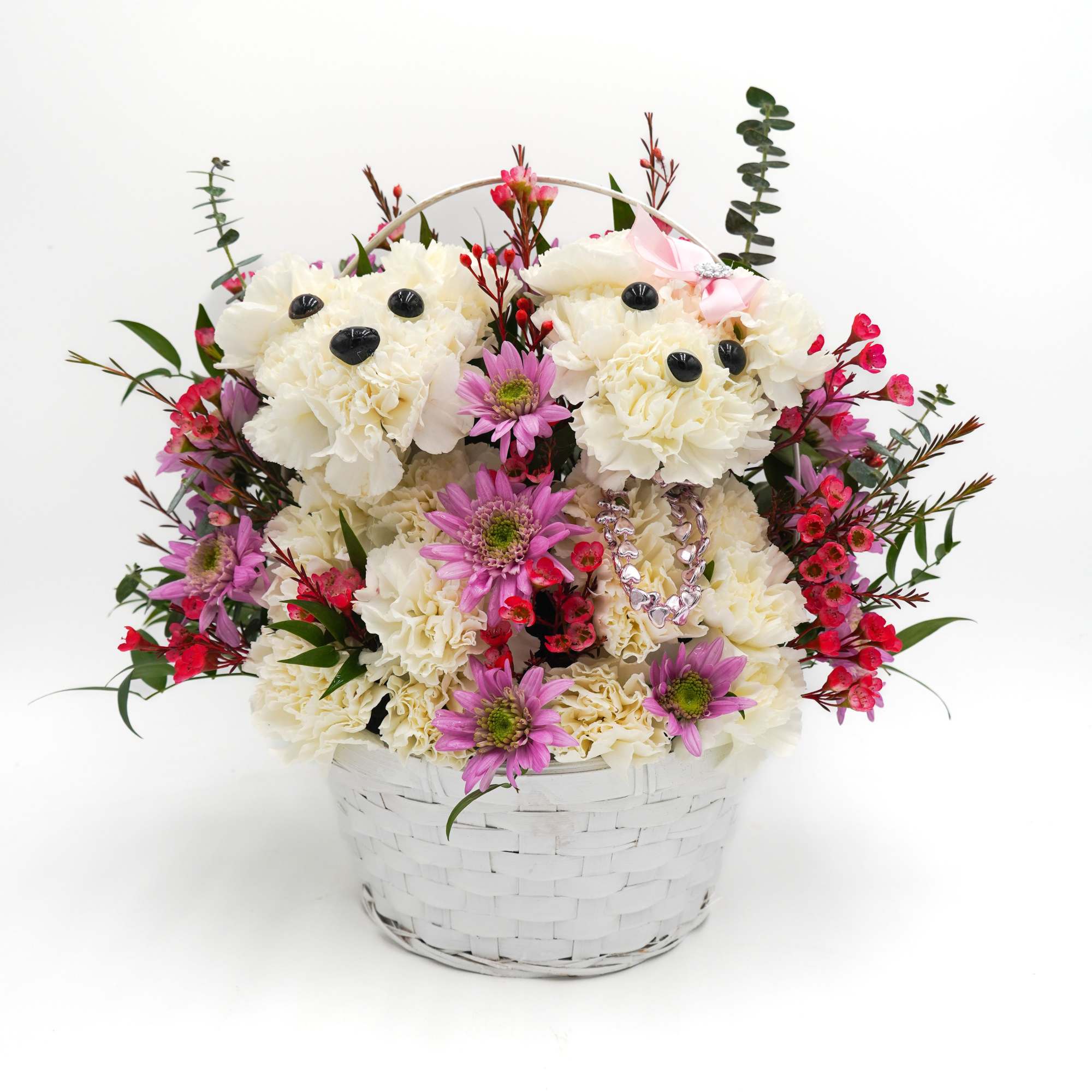 White flower arrangement in a white basket with pink accents and teddy bear faces