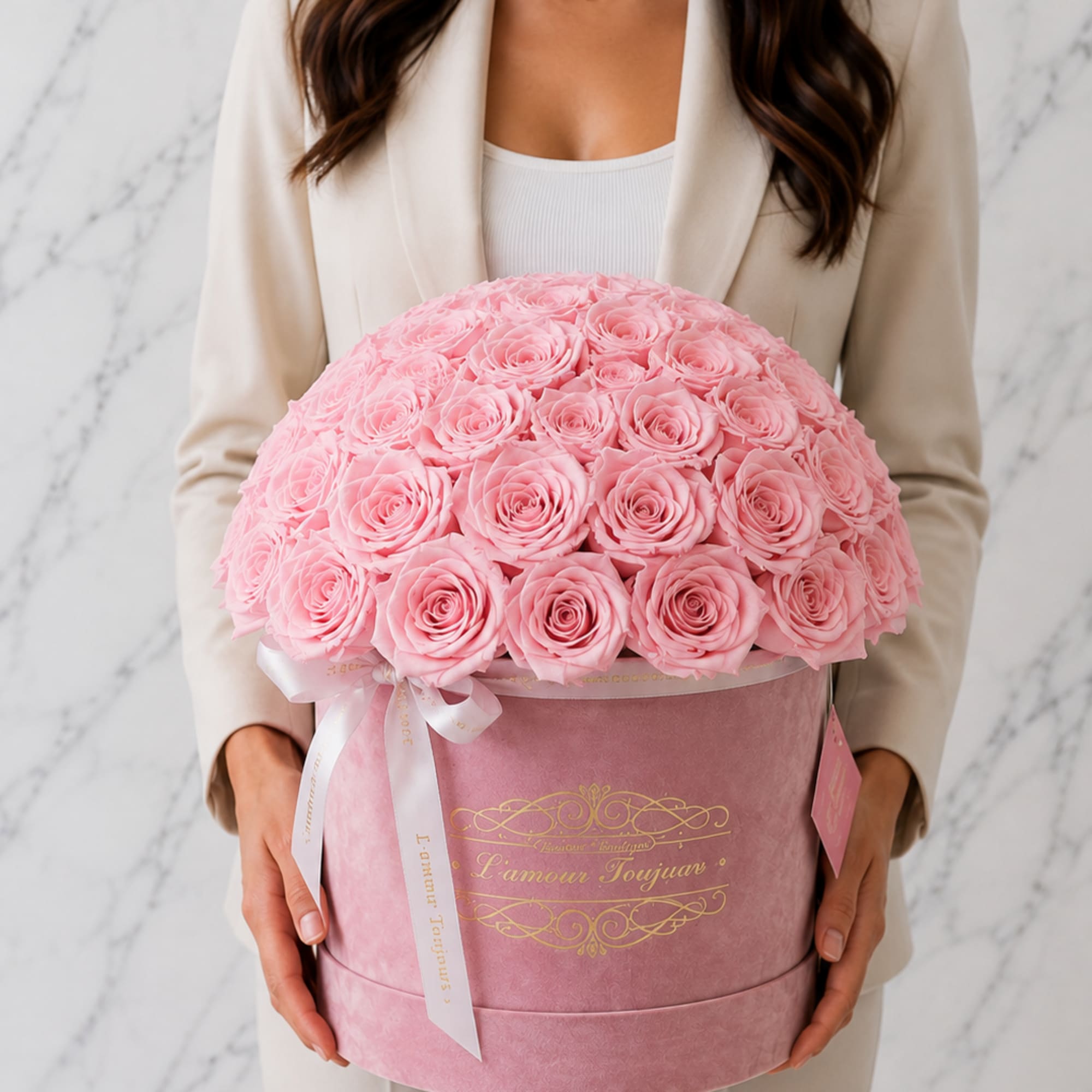 Woman holding a large pink rose bouquet in a round box