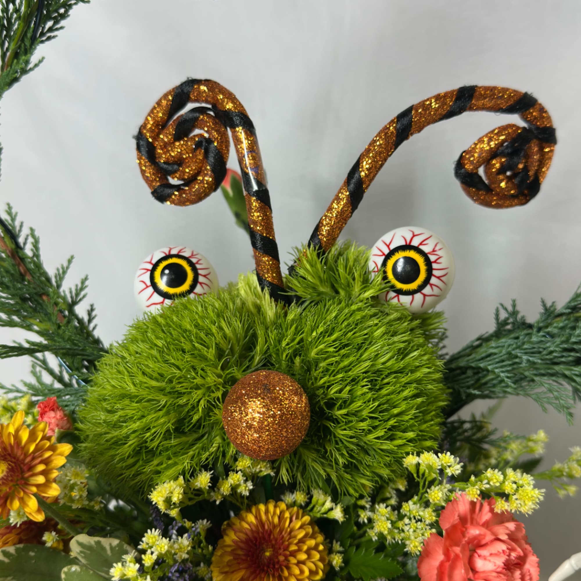 Whimsical floral arrangement with glittery curled antlers and googly eyes