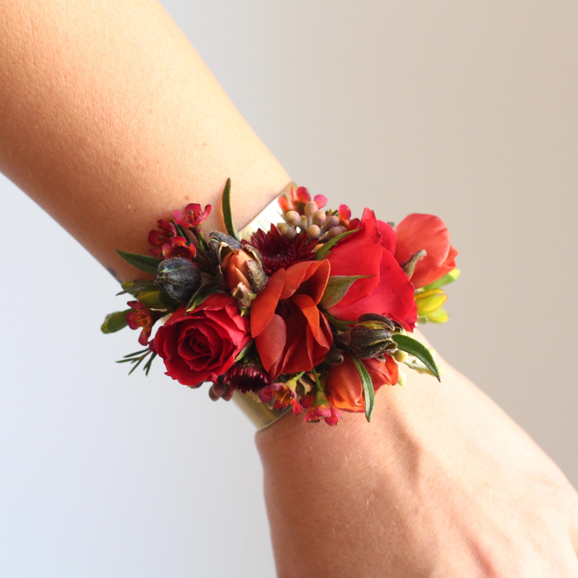 Red and orange wrist corsage with small flowers on a wristband