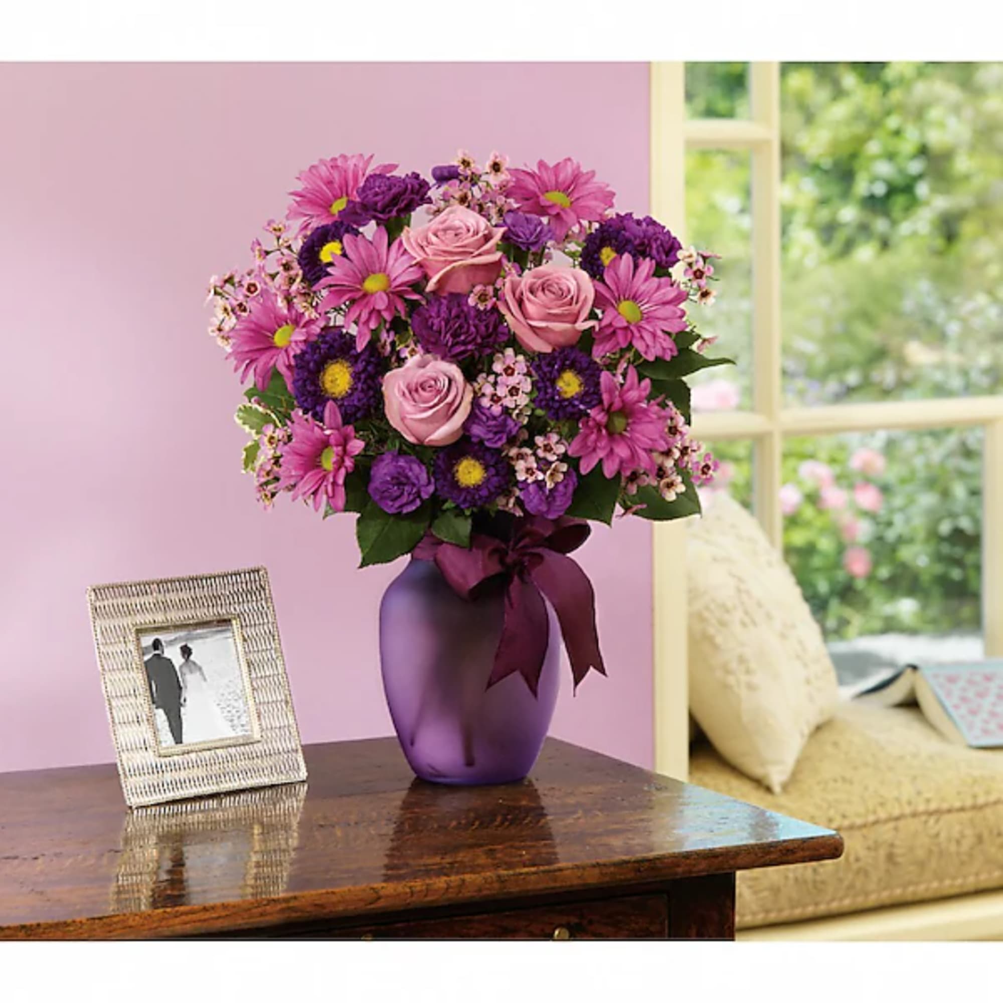 Pink and purple mixed bouquet in a purple vase on a table