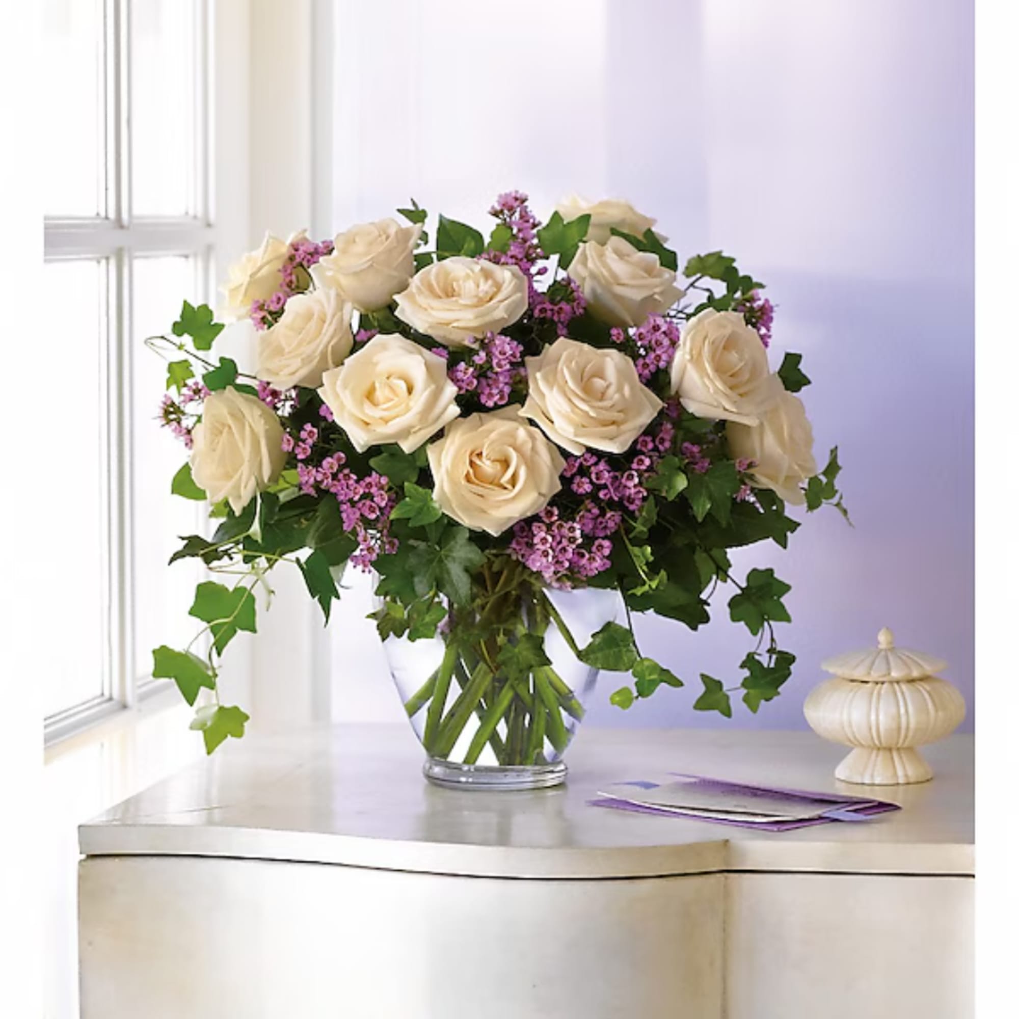 Cream roses and pink filler flowers in a clear glass vase