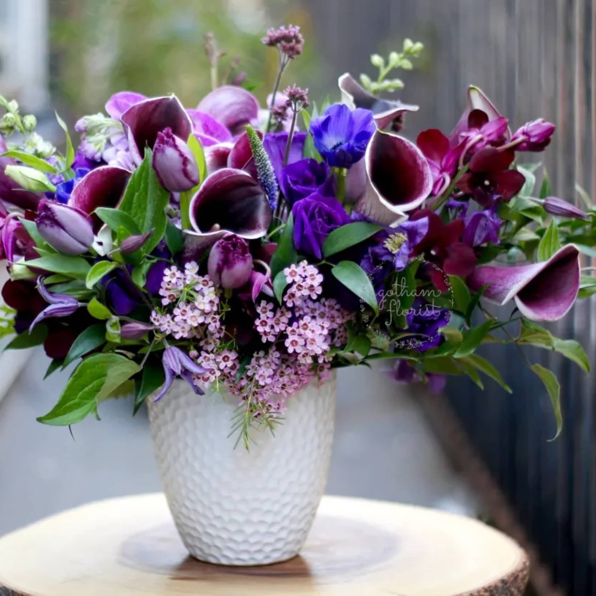 Purple and pink floral arrangement in a white textured vase