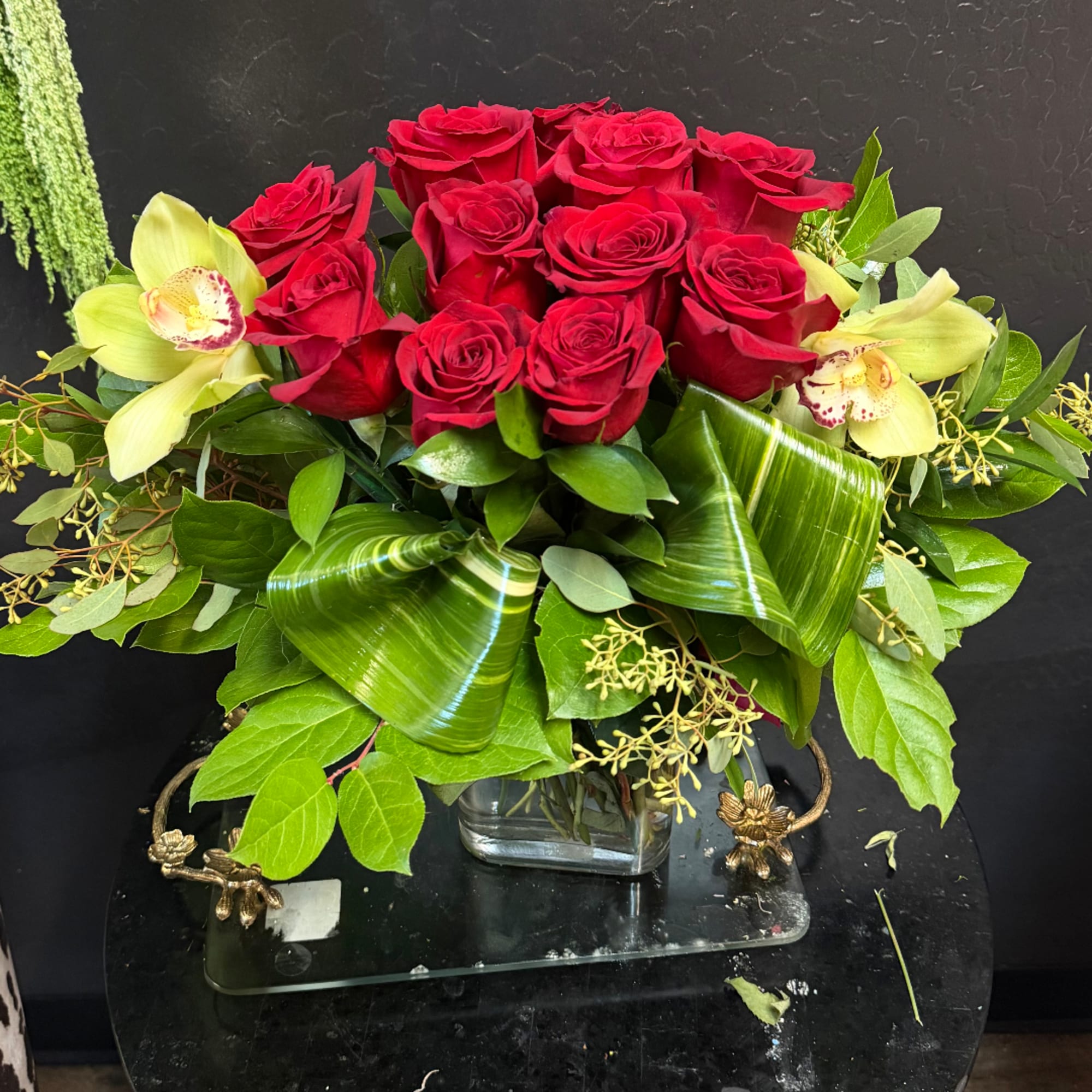 Red roses with pale yellow orchids in a glass vase