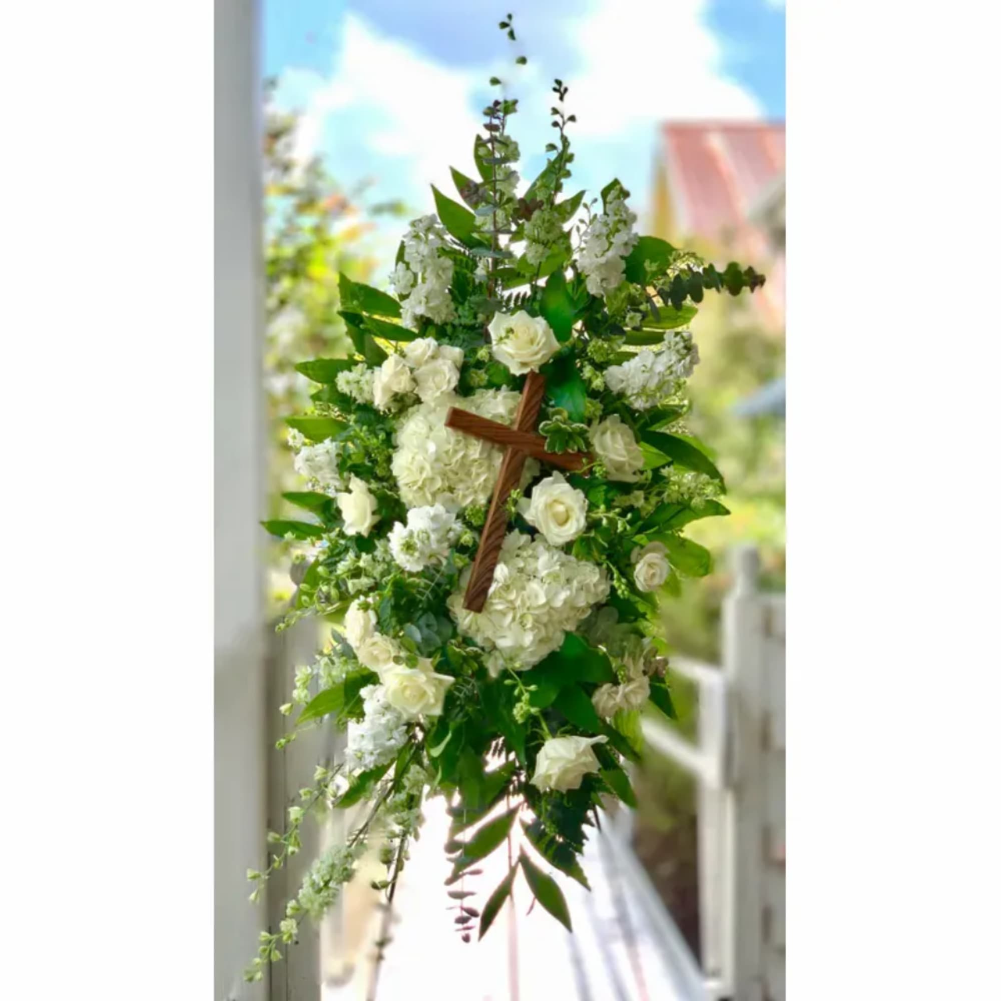 White floral cross arrangement with roses and hydrangeas