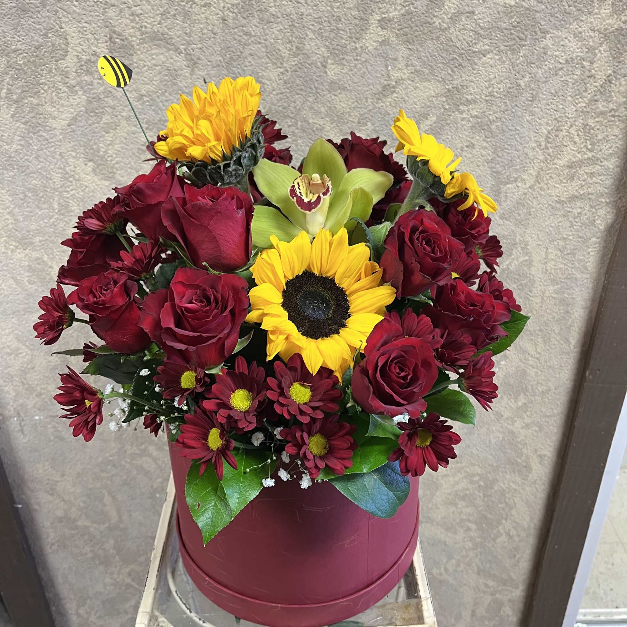 Bouquet of red roses and yellow sunflowers in a round box