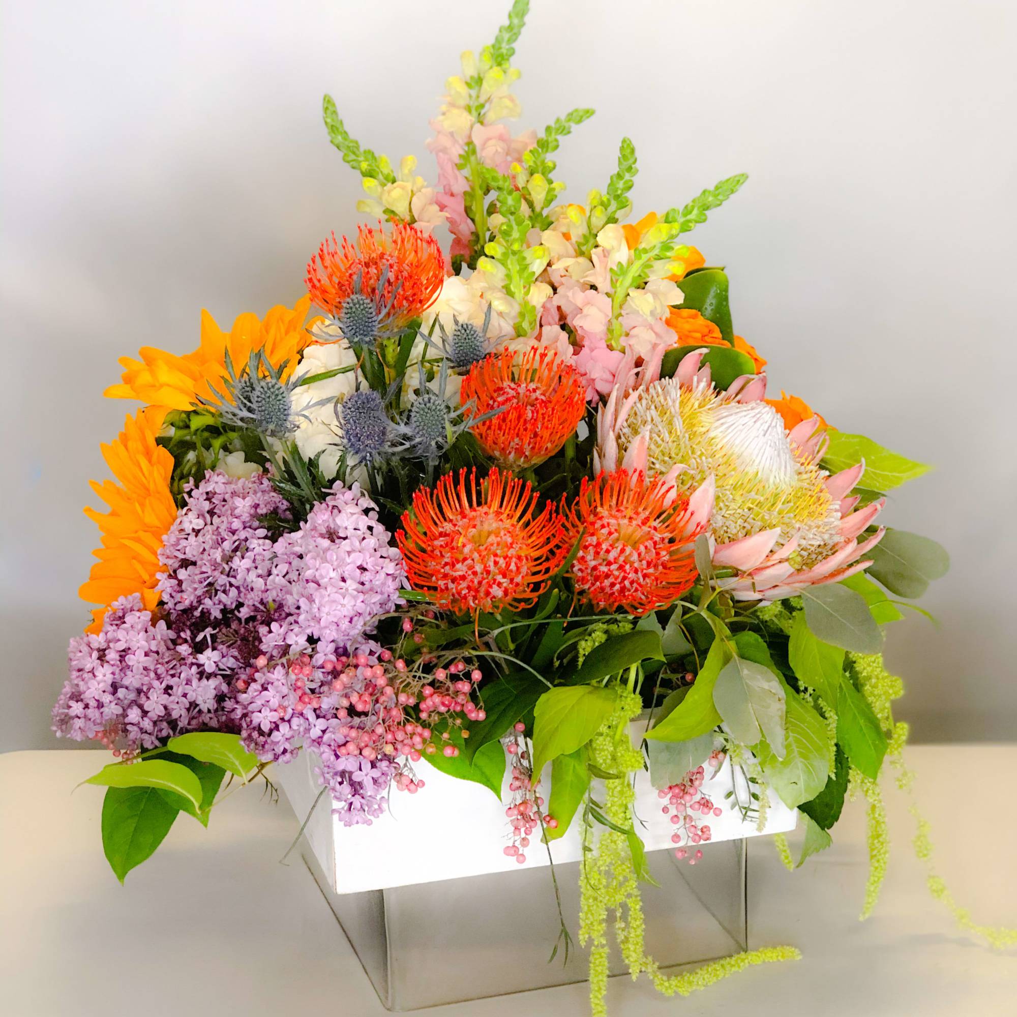 Colorful mixed flower arrangement in a white box vase