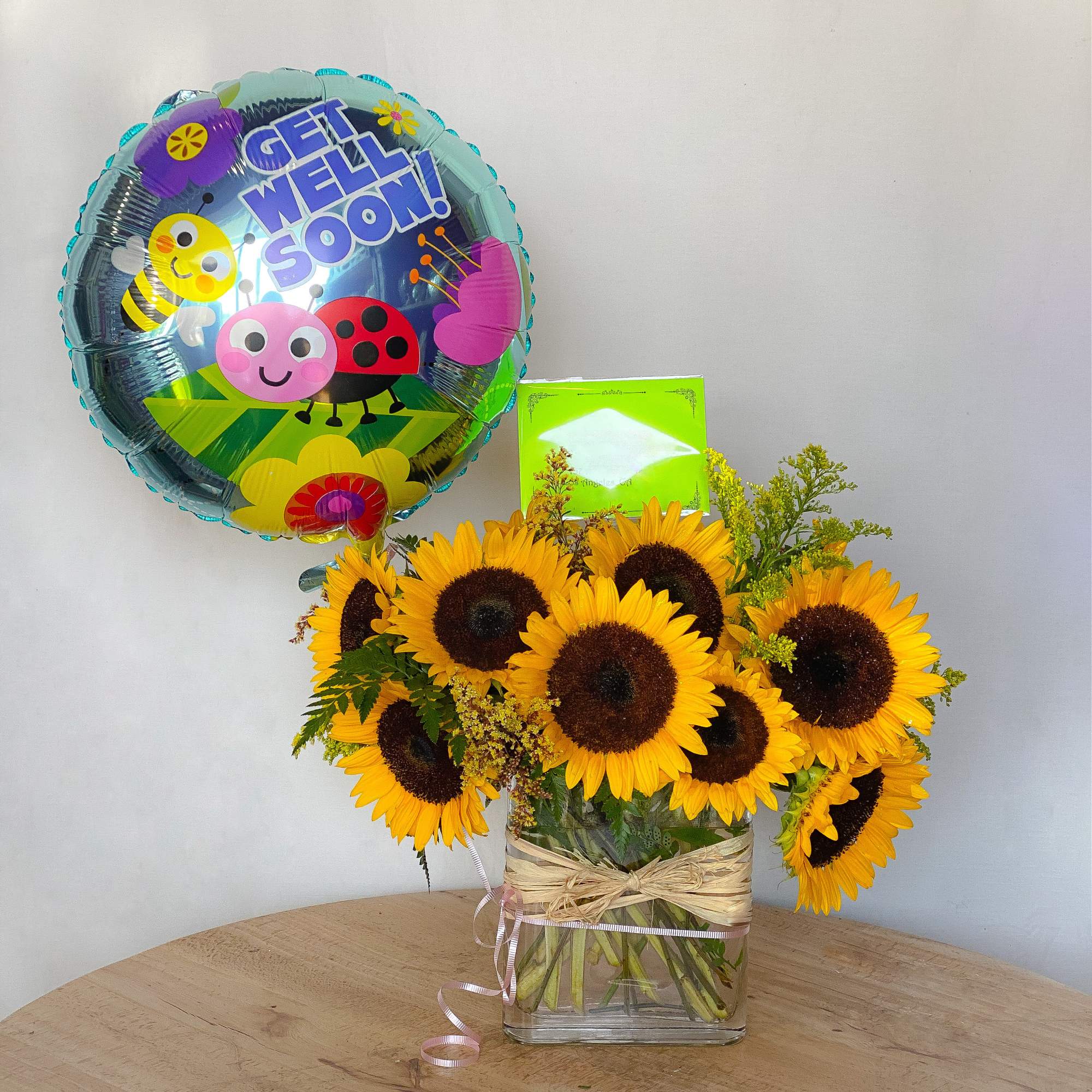 Sunflower bouquet in a glass vase with a bee balloon