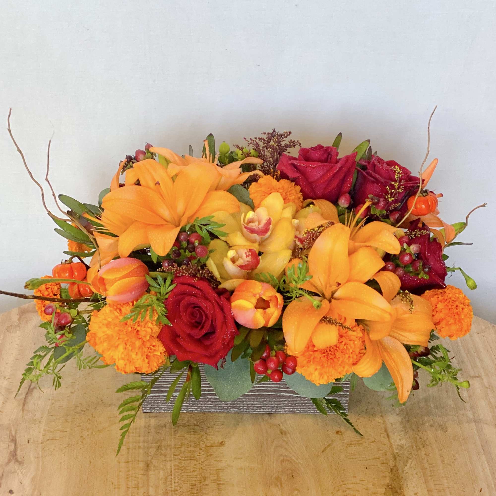 Bright orange and red floral arrangement in a rectangular container