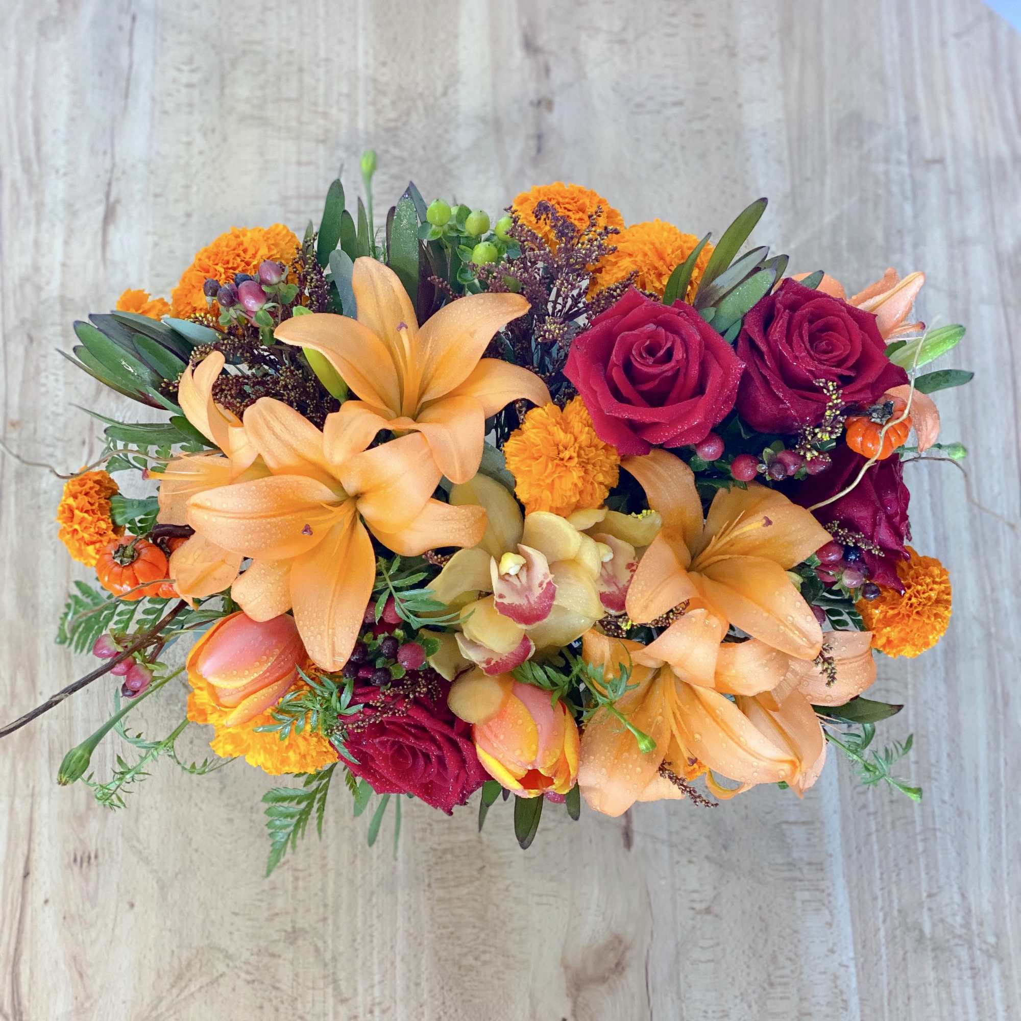 Bouquet of orange lilies and magenta roses with small orange blooms