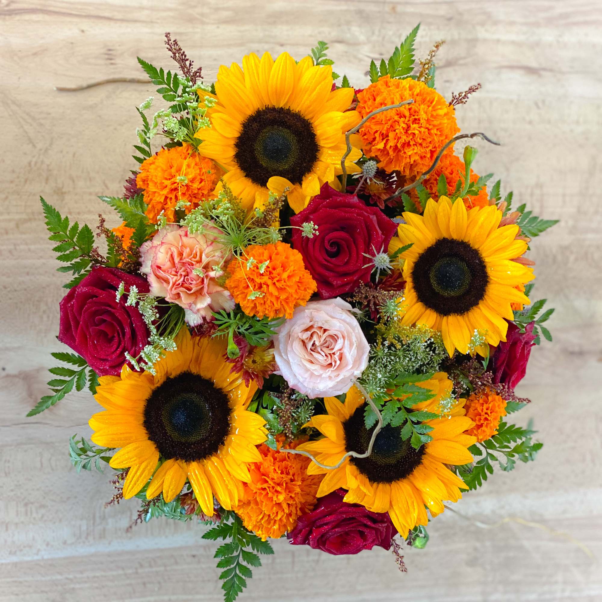 Bouquet of sunflowers, roses, and orange carnations