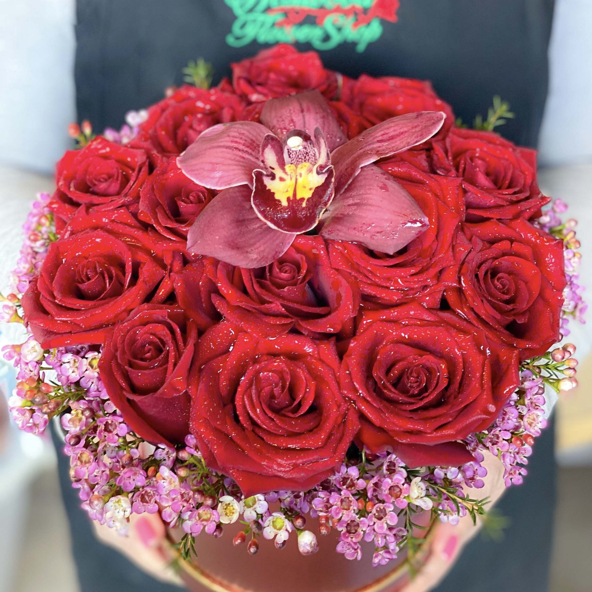 Red rose bouquet with a central orchid in a round box