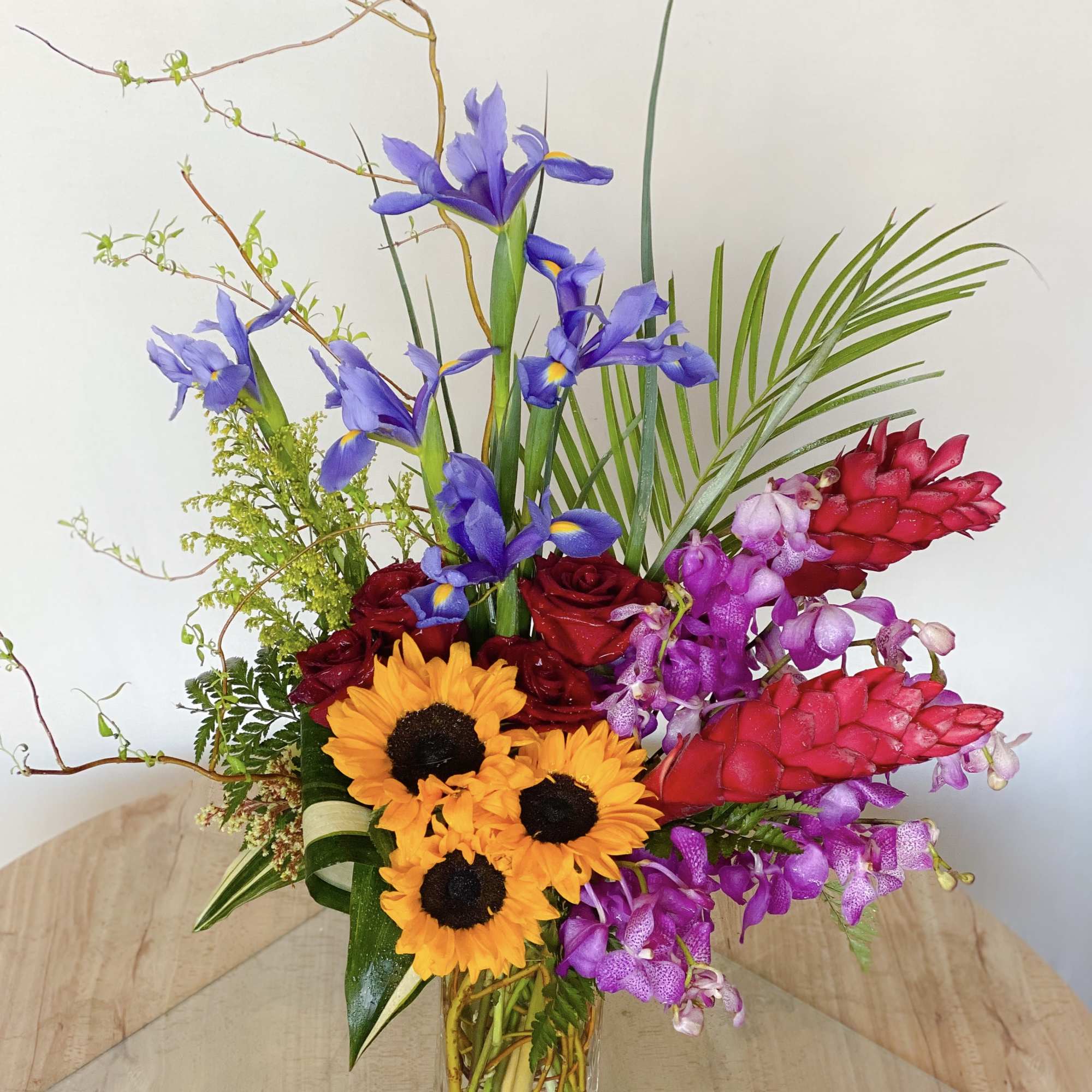 Colorful bouquet with sunflowers, roses, irises, and orchids in a glass vase, photo 4 of 4