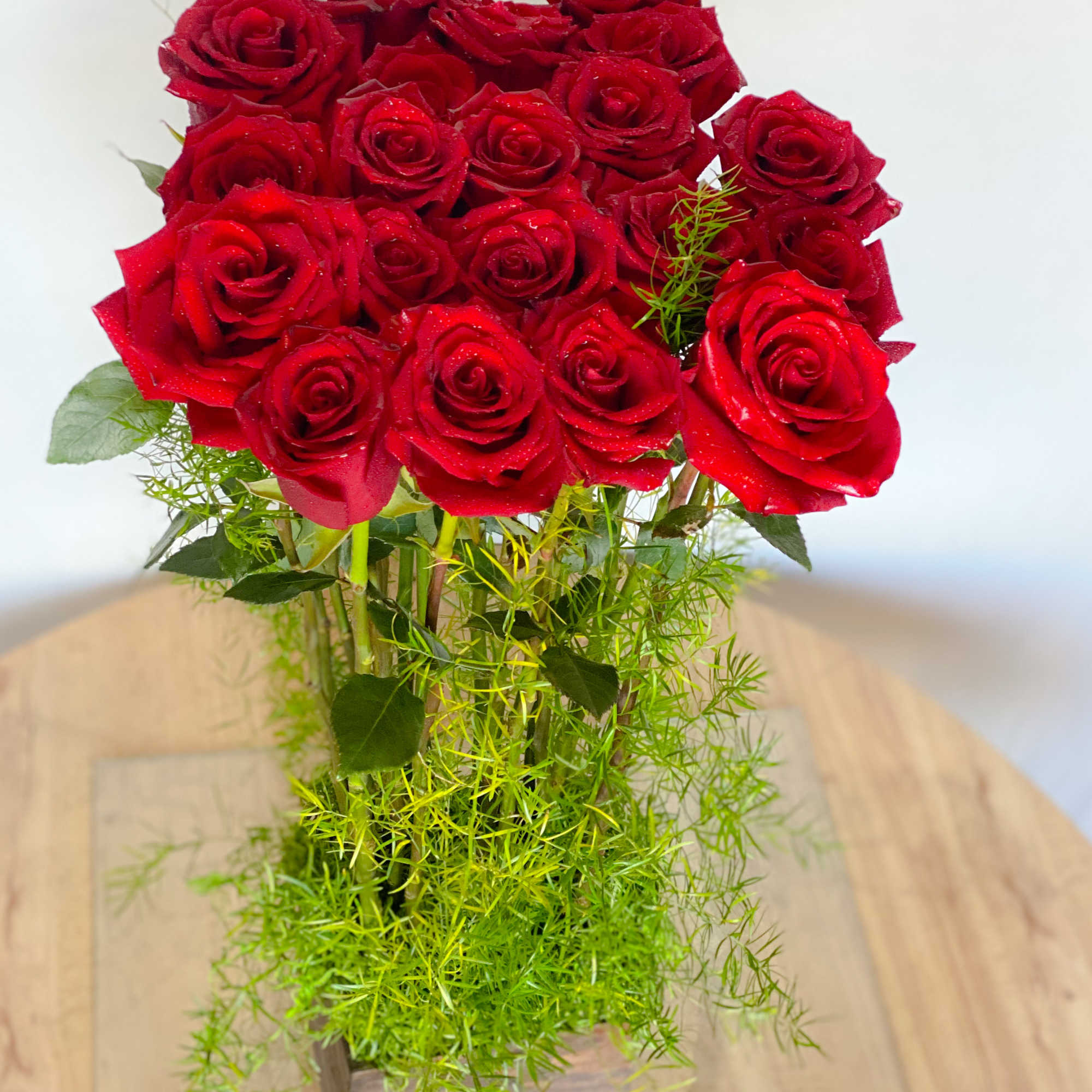 Bouquet of red roses in a clear vase with airy greenery