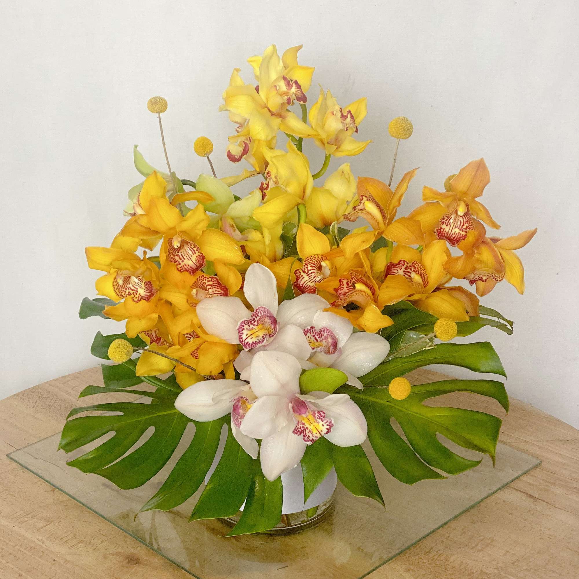 Yellow and white orchid arrangement in a low glass vase