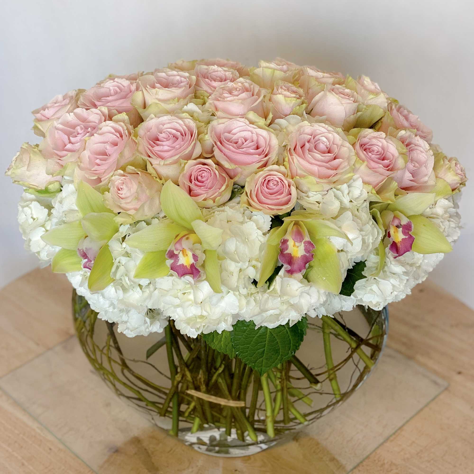 Pink roses and white orchids in a round glass vase