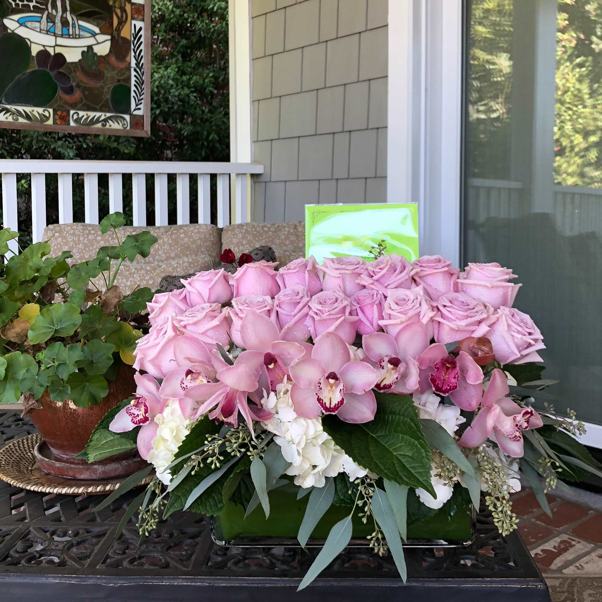 Pink roses and orchids arranged in a low rectangular container