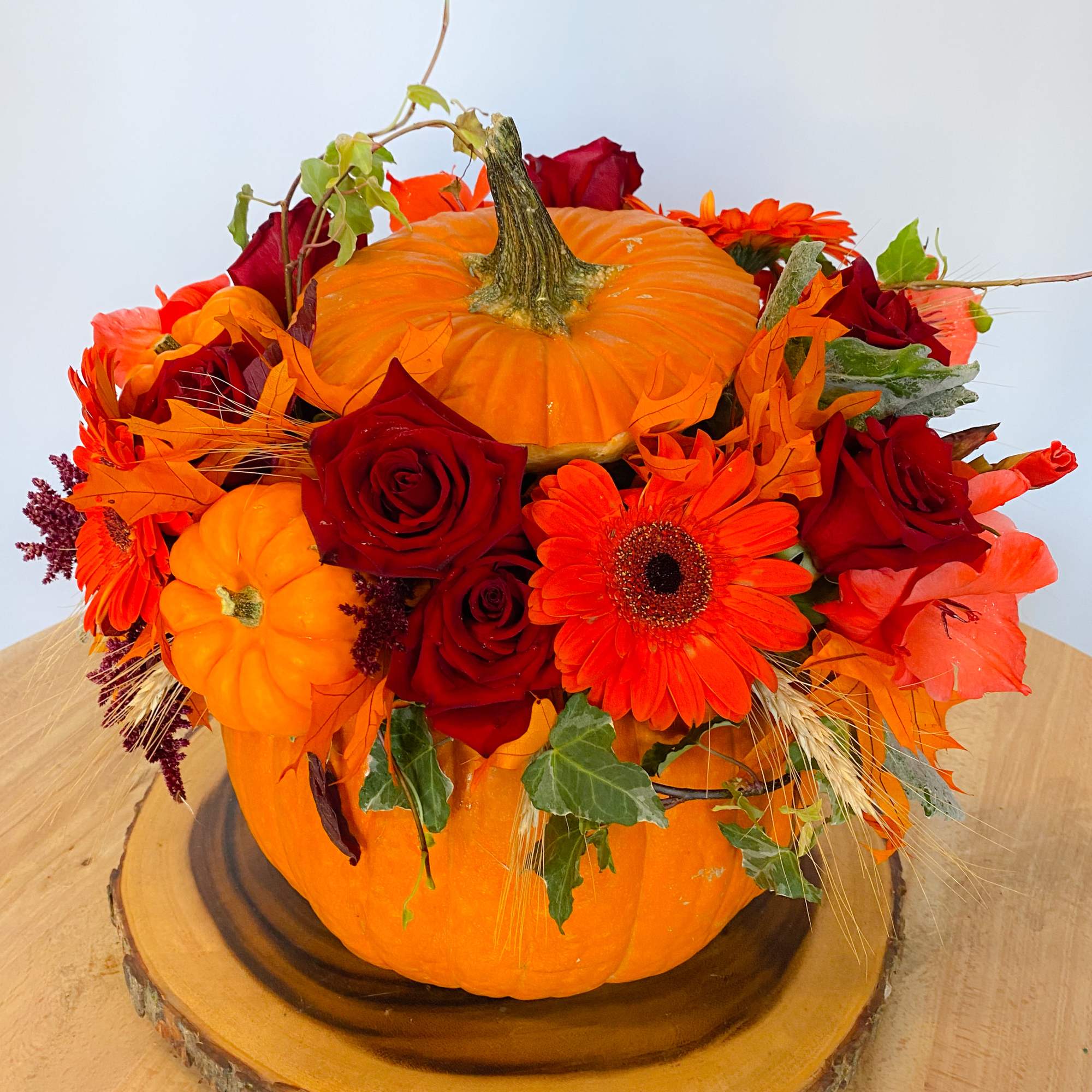 Pumpkin centerpiece with red roses and orange daisies