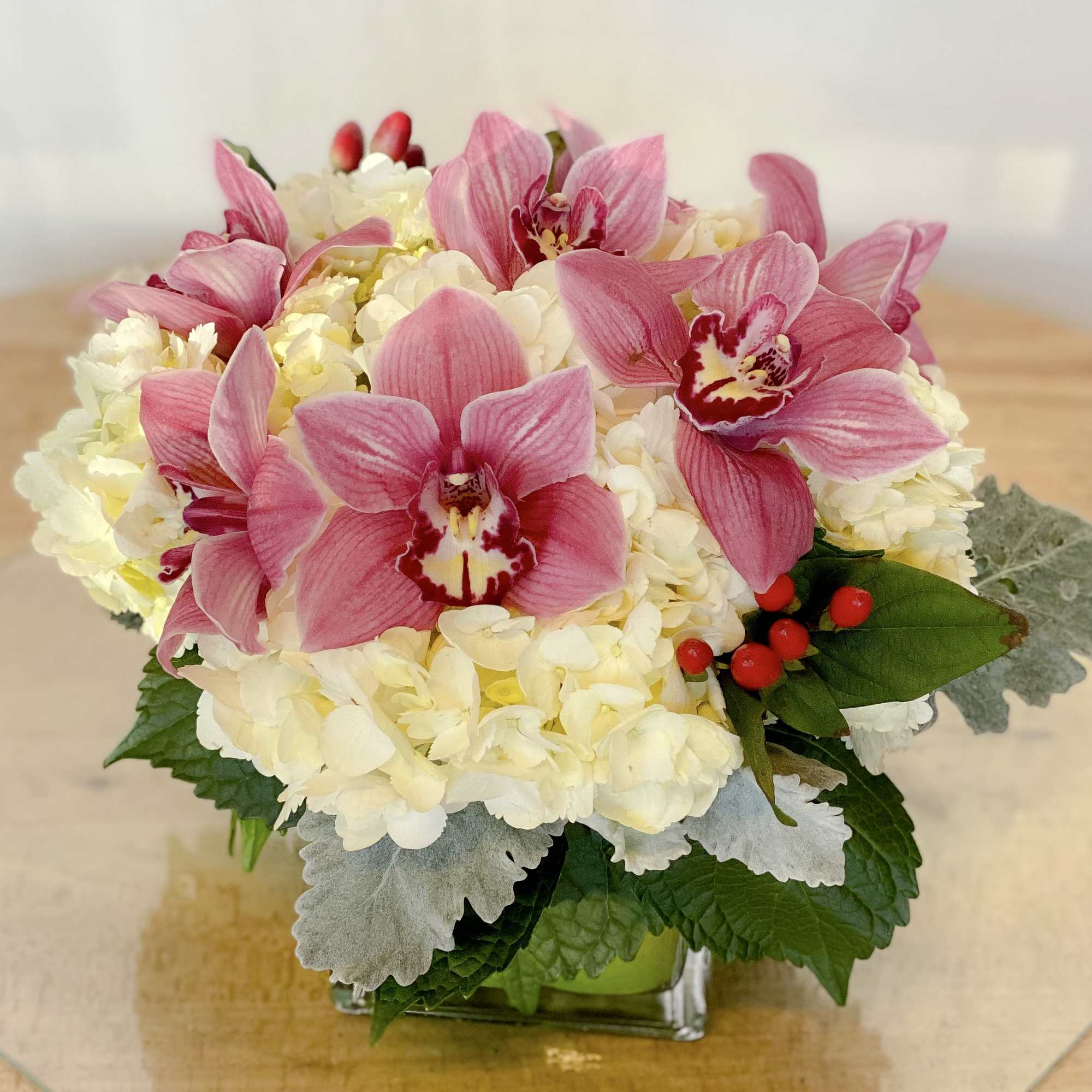 Pink orchids and white hydrangeas in a square glass vase