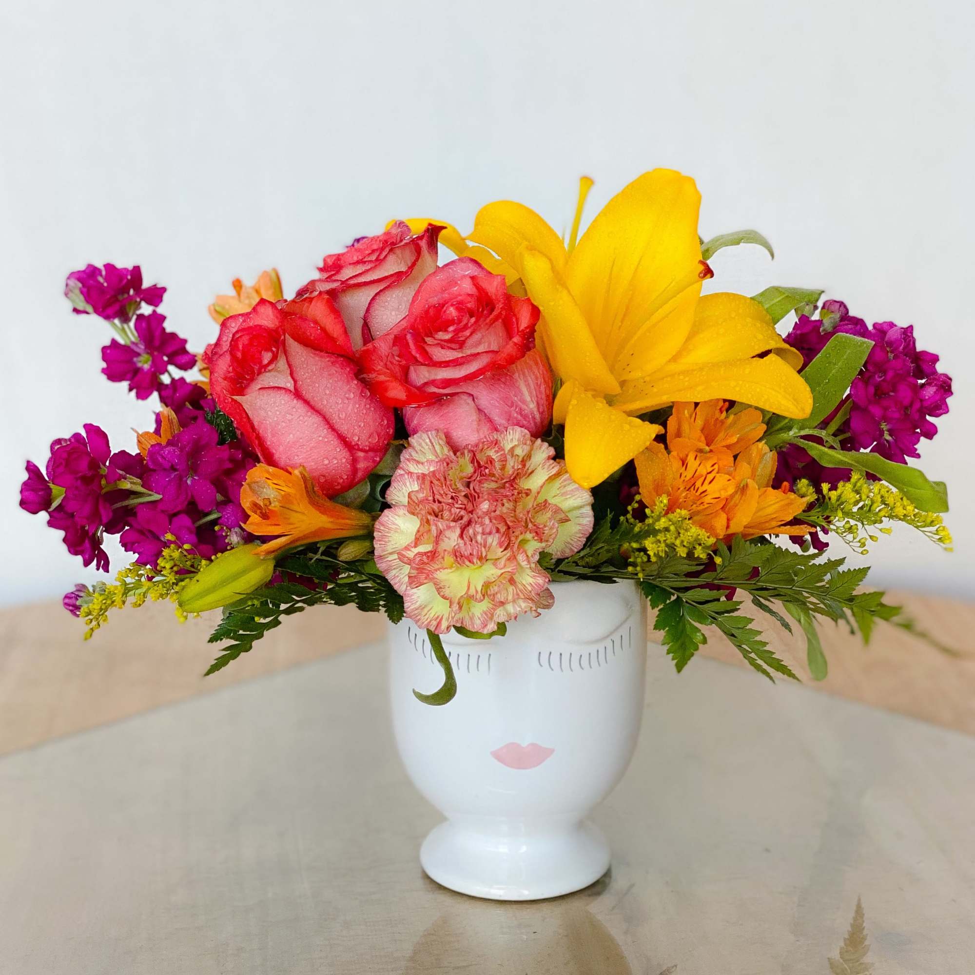 Colorful bouquet of roses, lilies, and carnations in a white vase