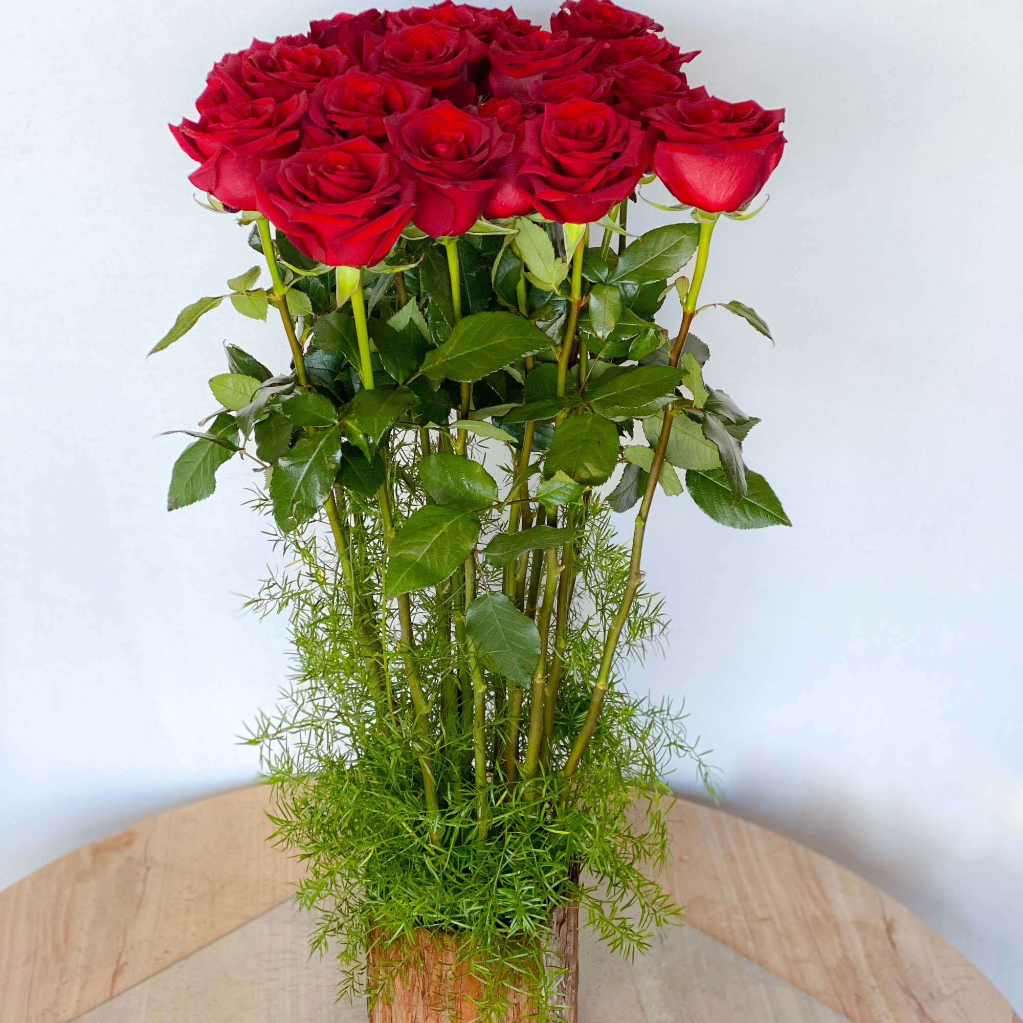 Tall bouquet of red roses in a wooden vase