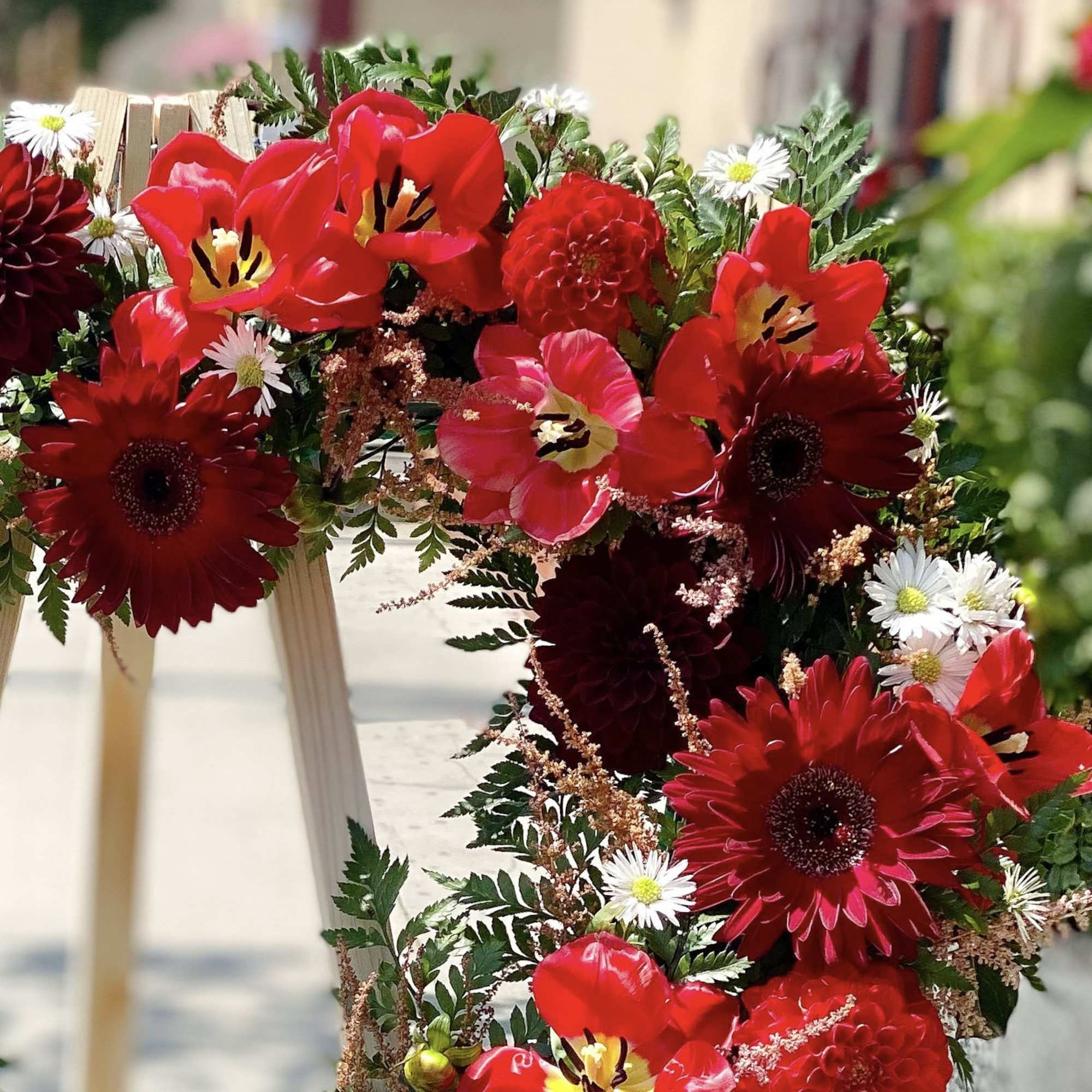 Red floral wreath with tulips, gerbera daisies, and small white daisies