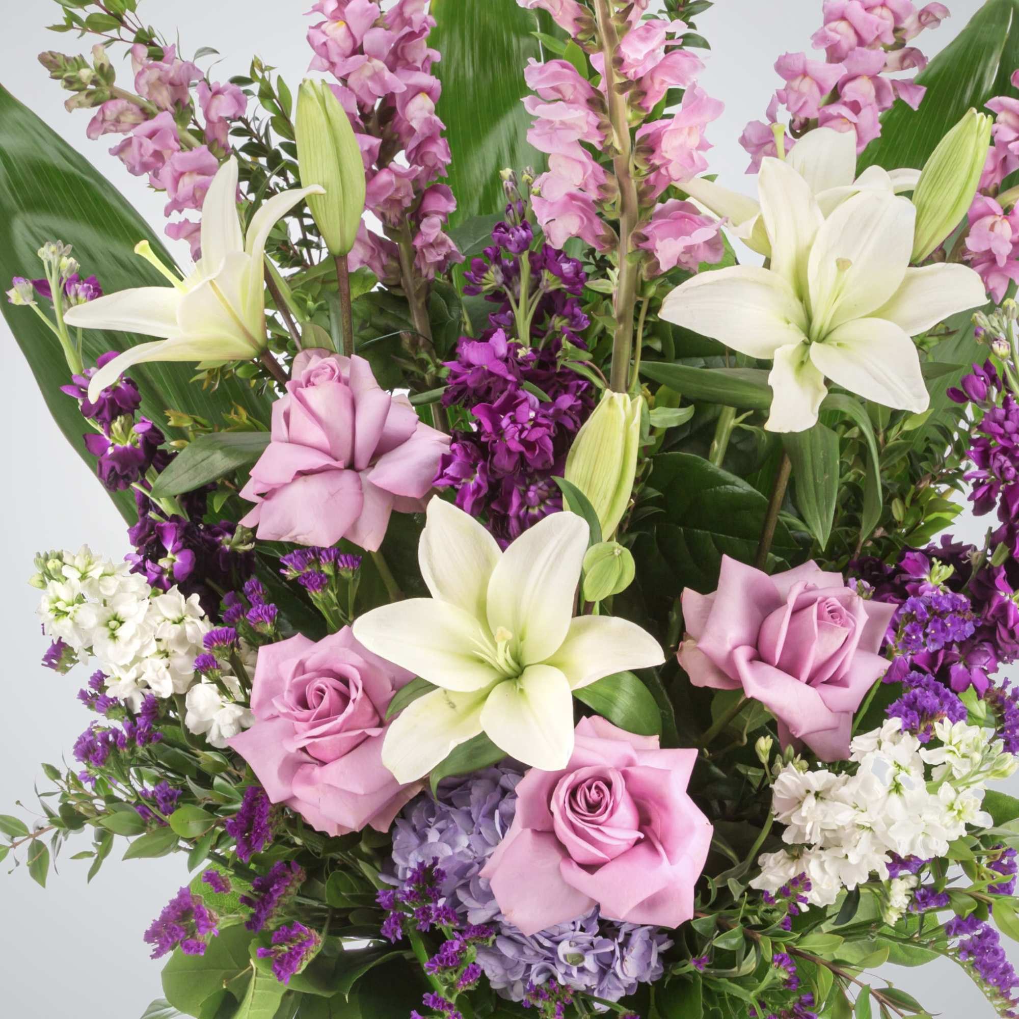 A purple and white sympathy basket featuring snapdragons, roses, lilies, and stock., photo 2 of 2