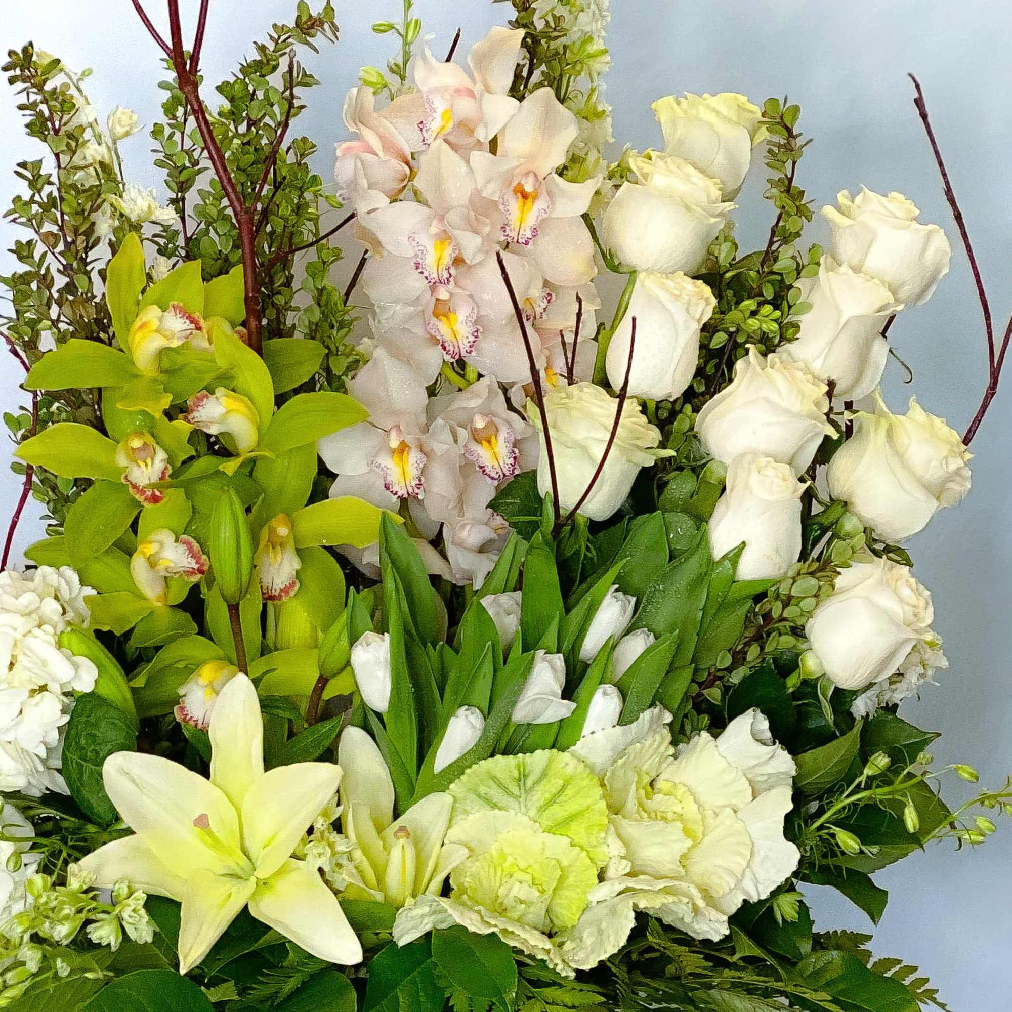 Bouquet of white roses, orchids, and pale lilies with green accents