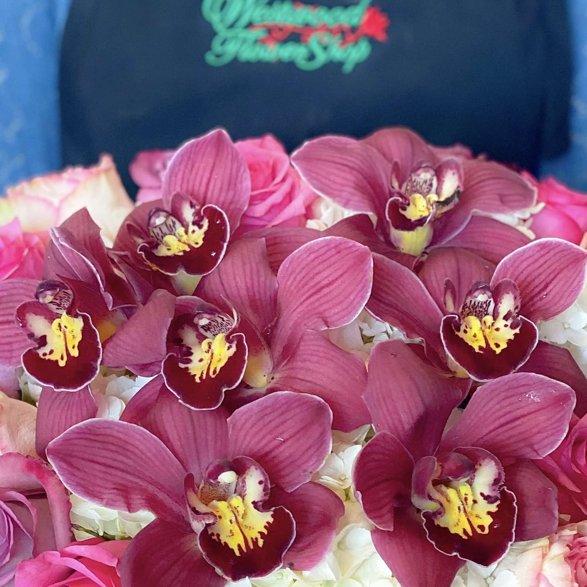 Pink orchids arranged over white and pink flowers in a gift box