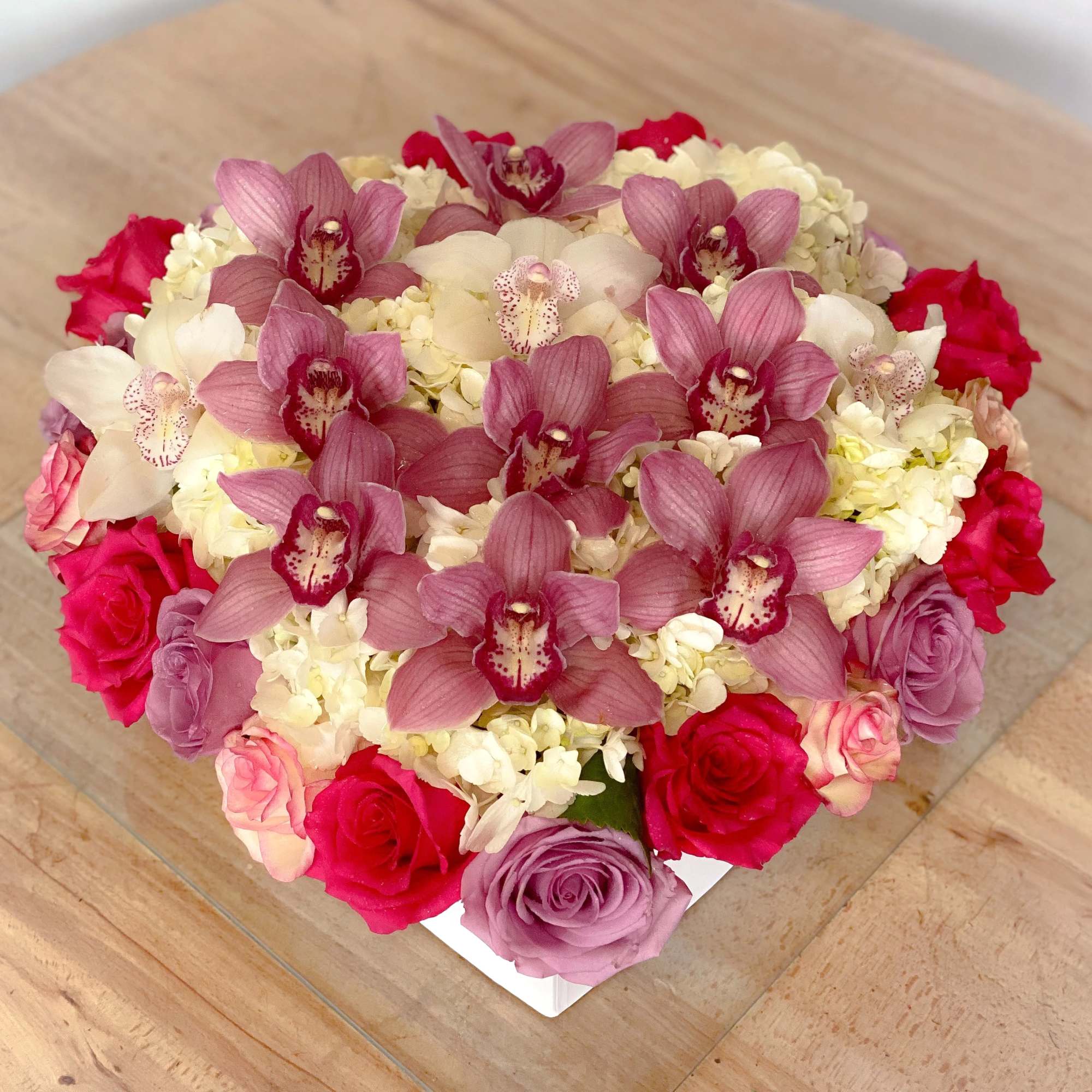 Heart-shaped bouquet of pink orchids, roses, and white hydrangeas