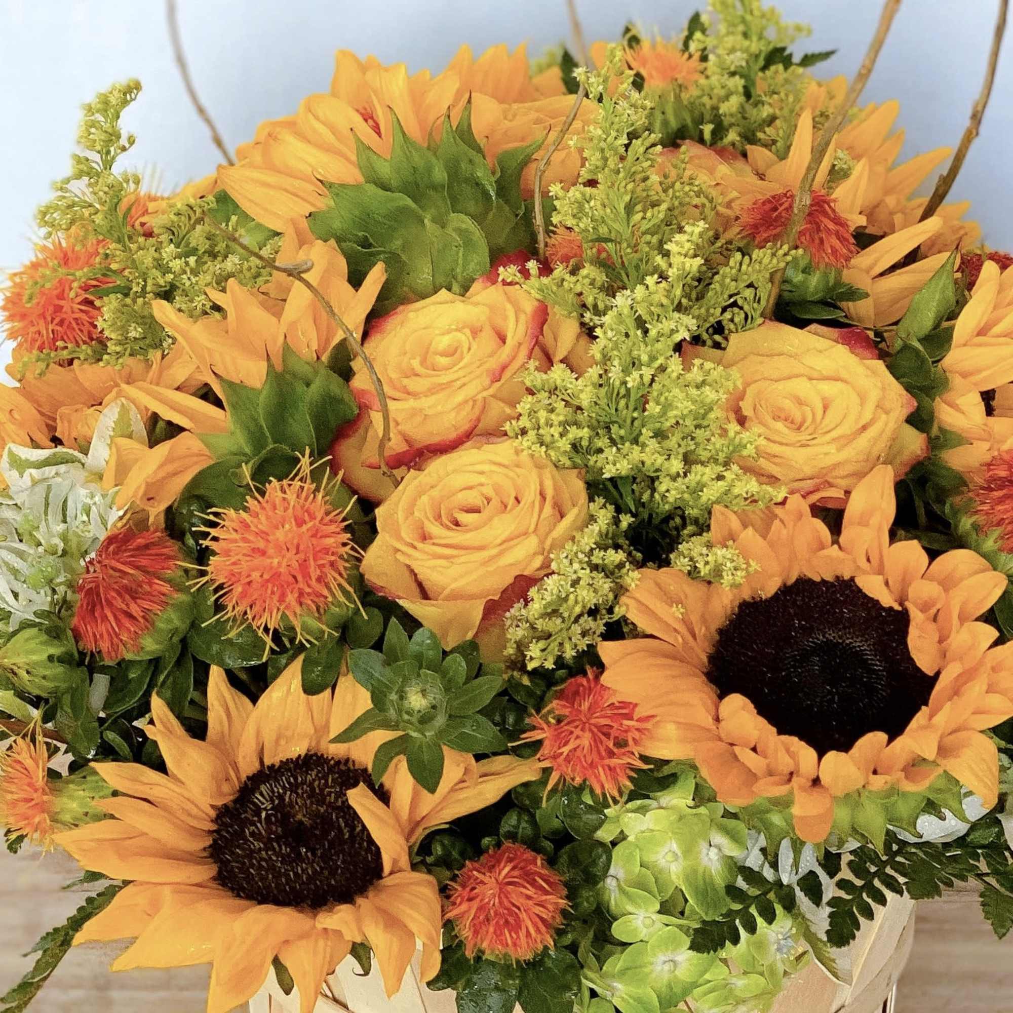 Bouquet of orange sunflowers and yellow roses with green filler