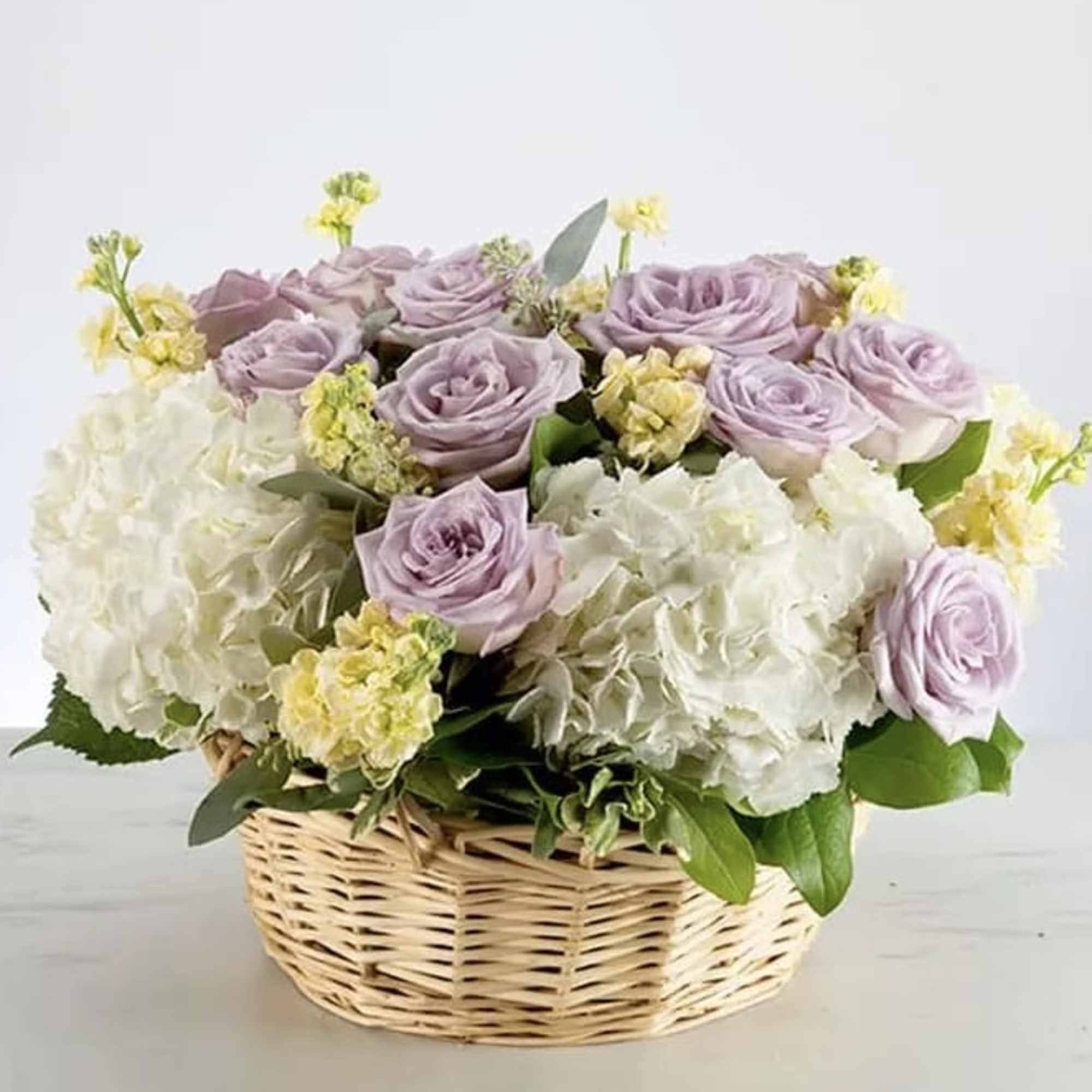 A basket full of blooming lavender roses and hydrangeas elegantly arranged in, photo 2 of 2